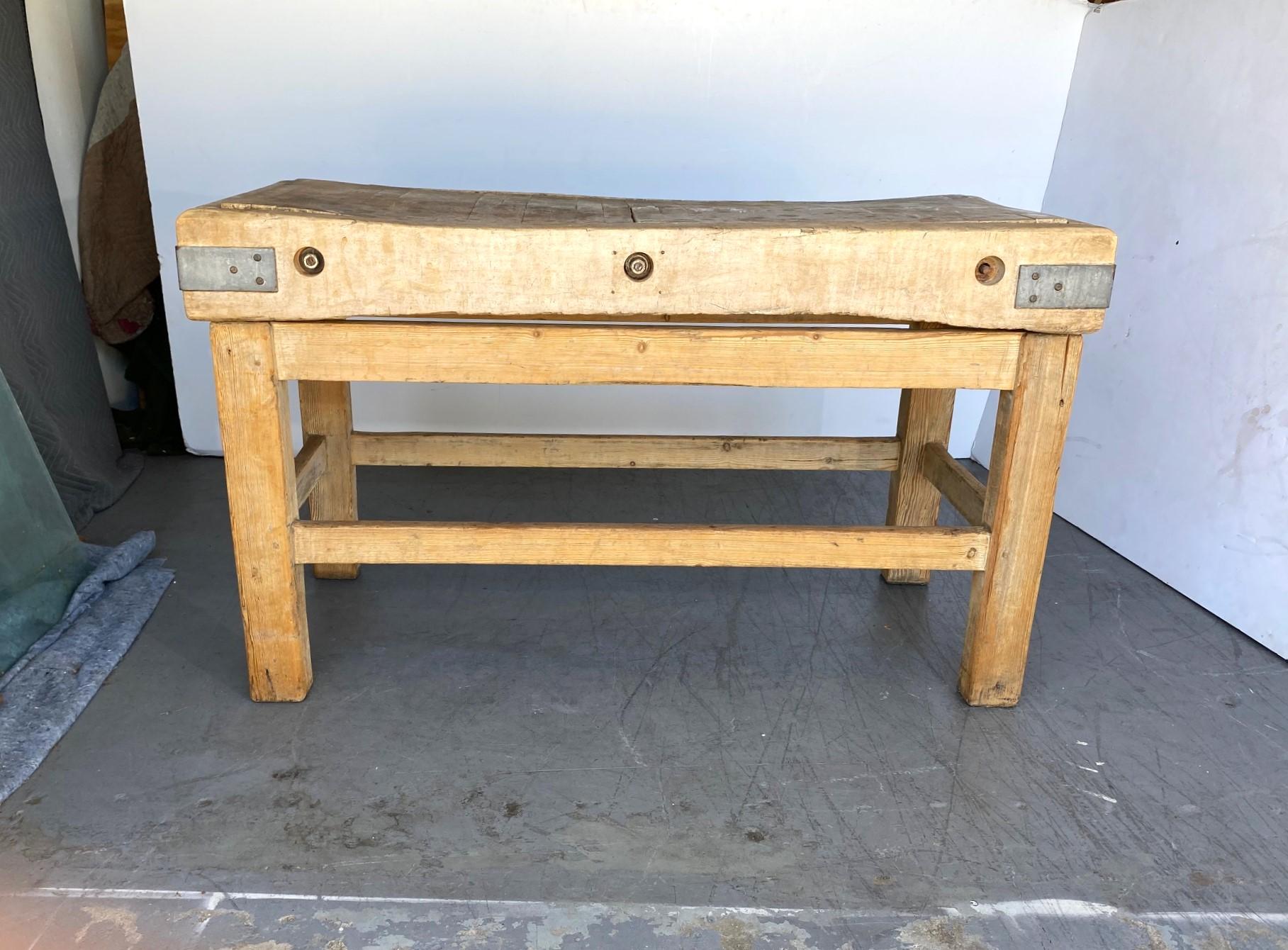  19th-century hand-crafted butcher's block sits atop a pine base which is very sturdy, with no movement at all. Iron straps at the corners and iron rods pass through the butcher block and lock it together. It is a beautiful piece that has gathered a