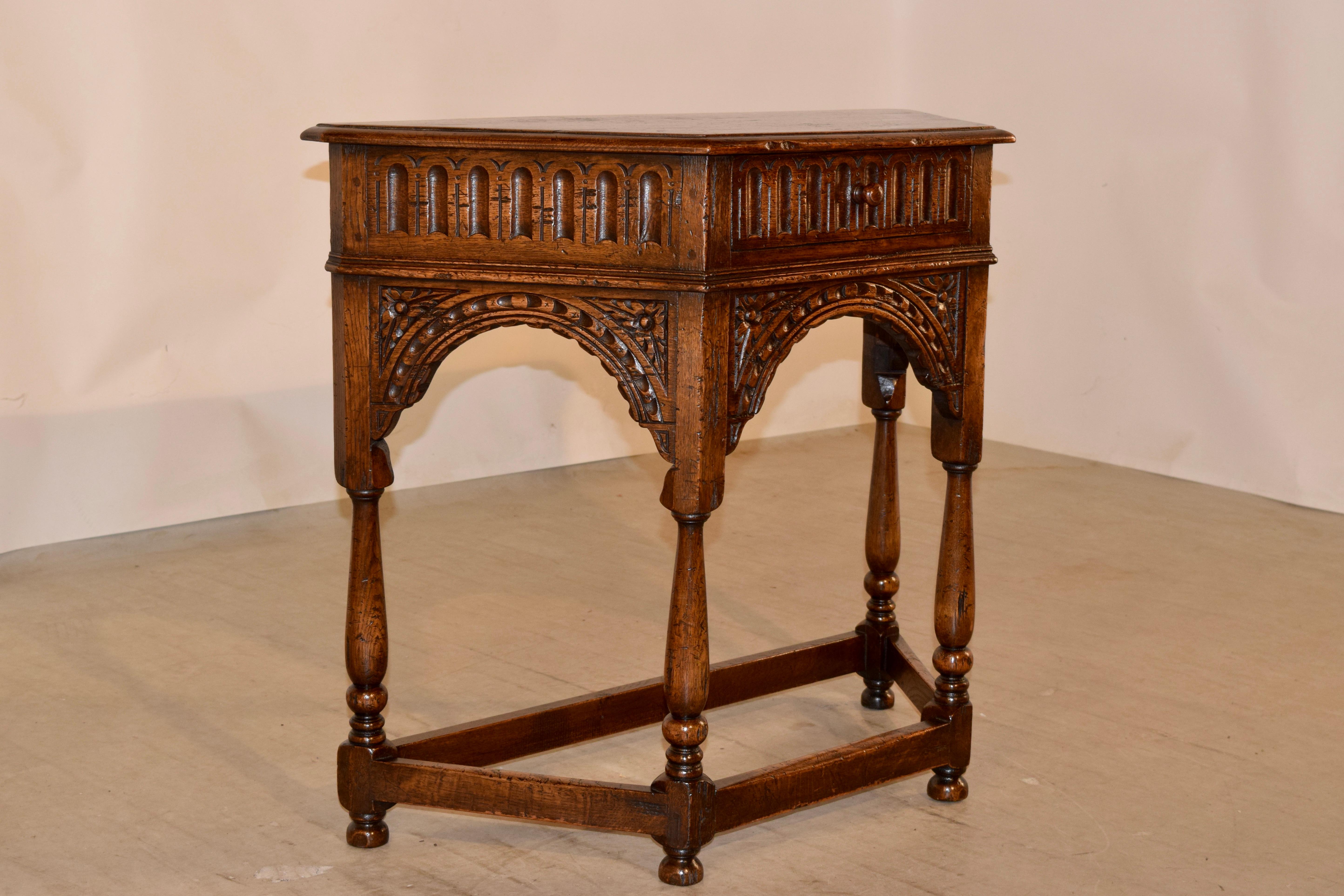 19th century oak table from England with a five sided top which has a beveled edge and following down to a hand carved decorated fluted apron, containing a single drawer in the front. This is over a carved canted apron on all three sides, for a