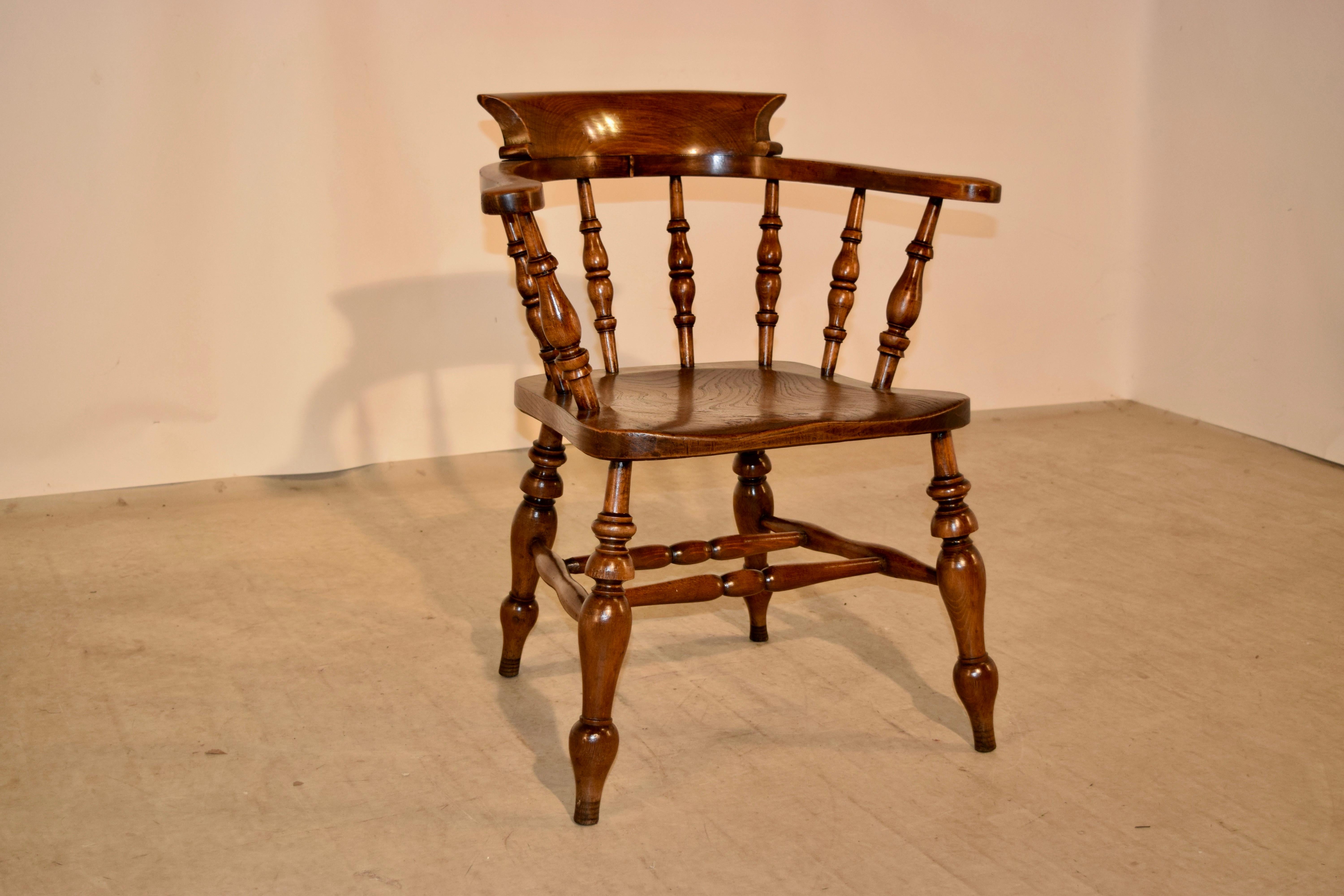 19th century English captain's chair with a shaped back and hand-turned spindles for a very comfortable seat. The chair seat is made of elm as well, and the entire chair is supported upon hand-turned splayed legs, joined by hand-turned stretchers.