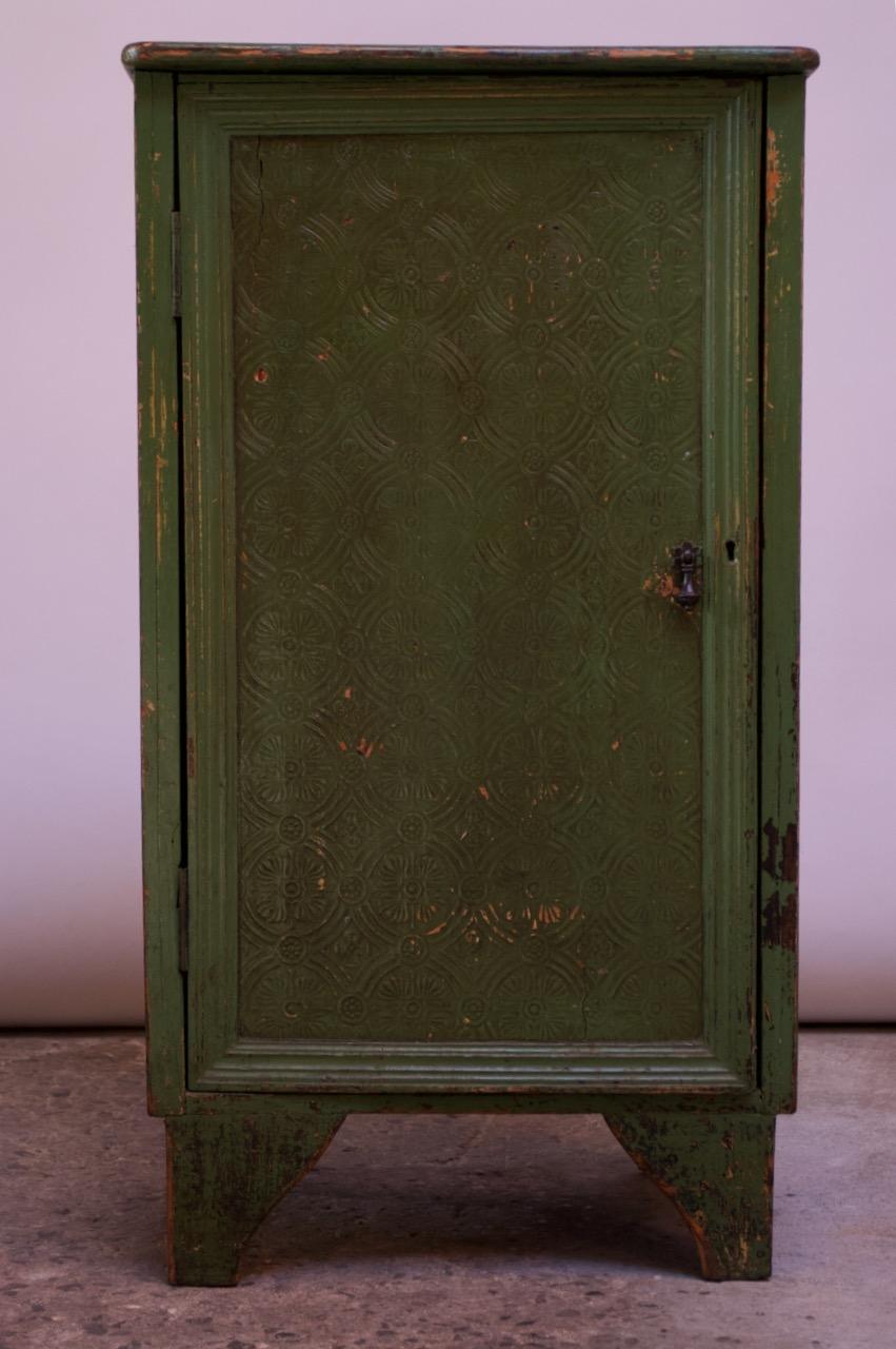 Diminutive painted pine jelly cupboard (circa late 1800s) composed of a plank-top with a hinged door concealing two fixed-shelves. Exterior retains its original green paint. Three sides boast an intricately carved floral motif throughout; the back