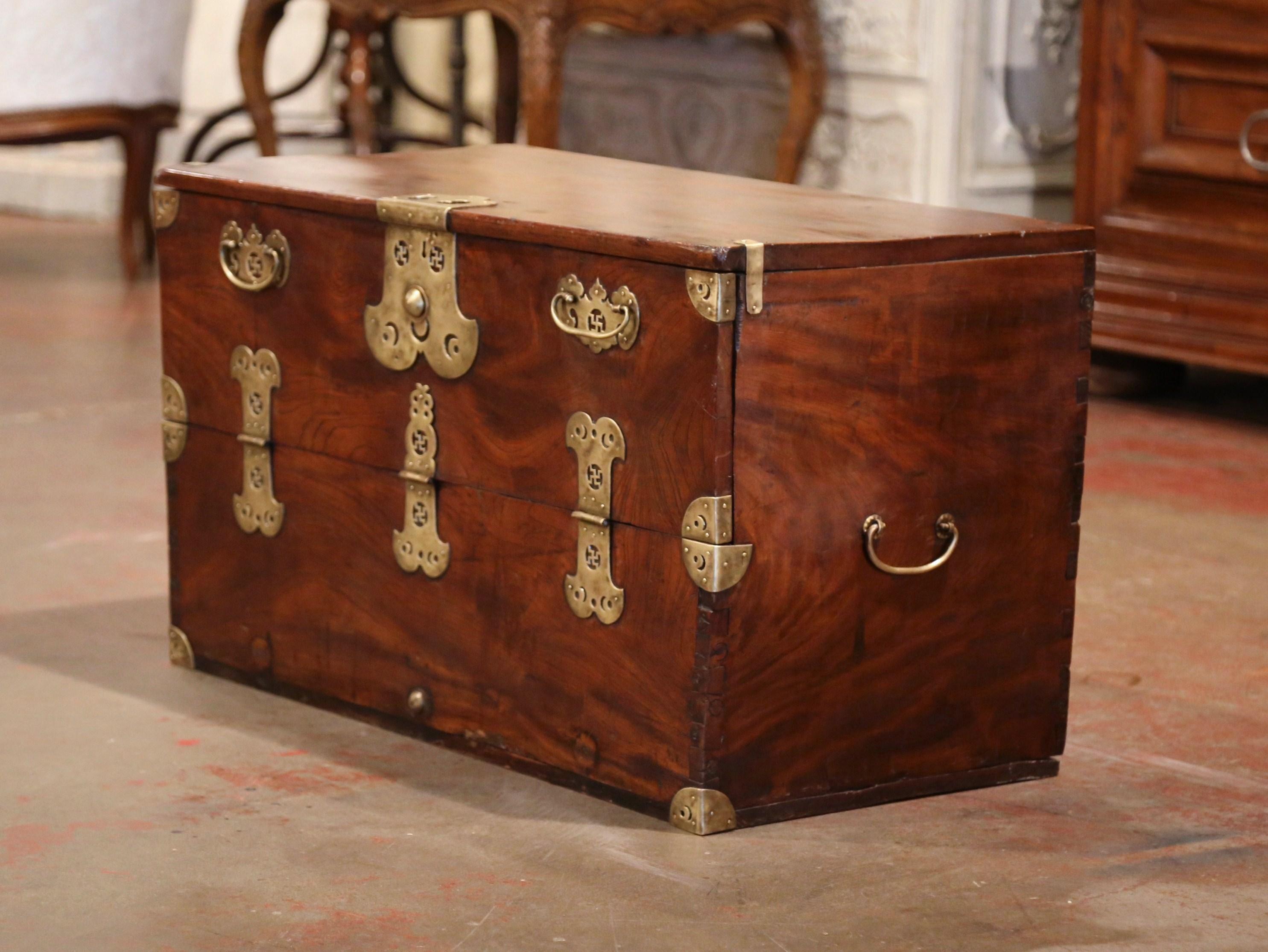 This elegant antique chest was created in England circa 1860; made of chestnut, and finished on all five sides including the back, the versatile trunk or cocktail table features a folding front door with inside storage and decorated with brass