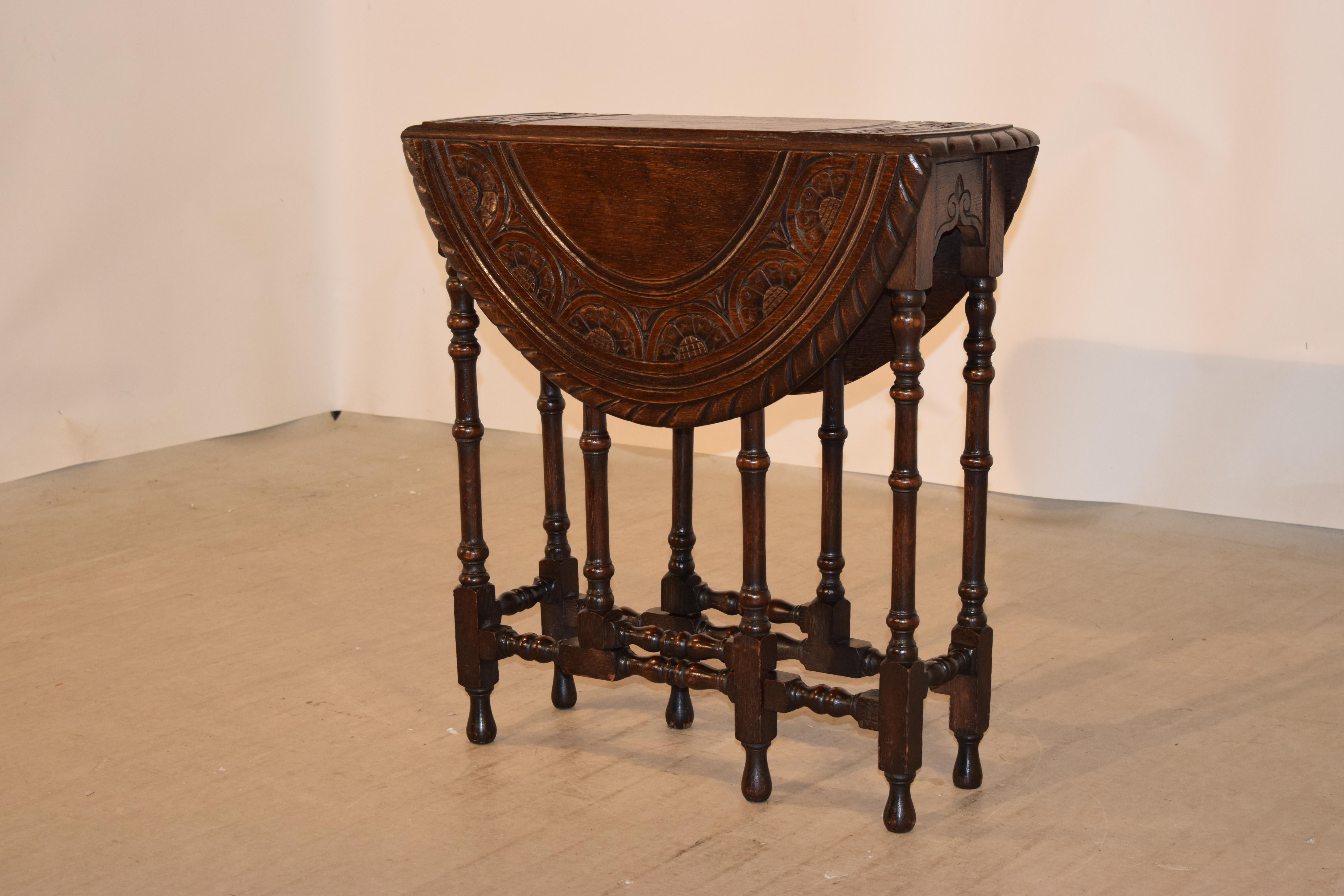19th century English oak gate leg table with a wonderfully hand carved decorated and beveled edge surrounding a hand carved border over a nicely scalloped and carved apron and hand-turned legs and gates, joined by matching hand-turned stretchers and