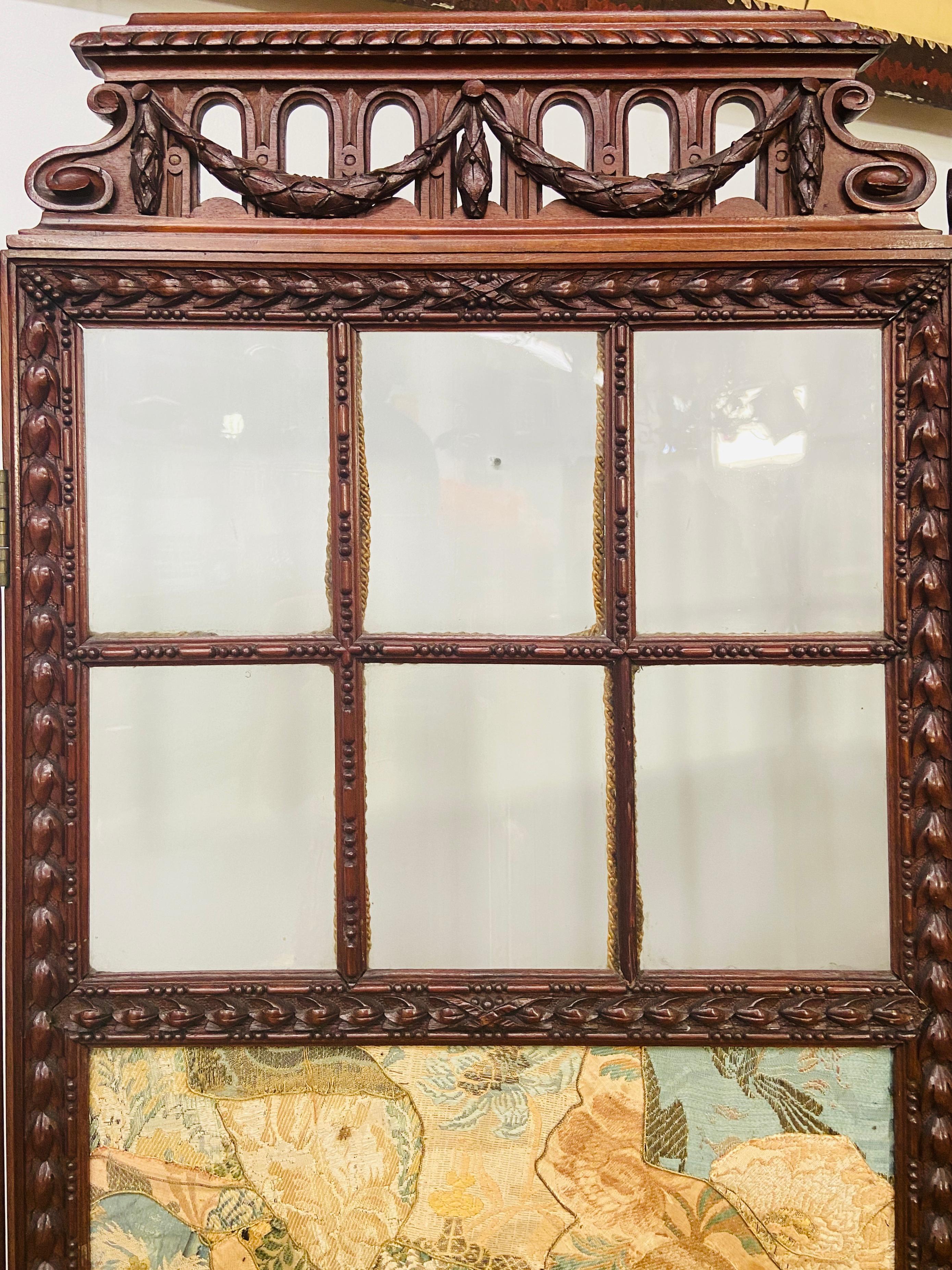 19th century English carved mahogany and glass four-panel room divider or screen

This antique four-fold upholstered divider or screen features a delicate acanthus leaf design carved mahogany and an original silk oriental motif upholstery. Each