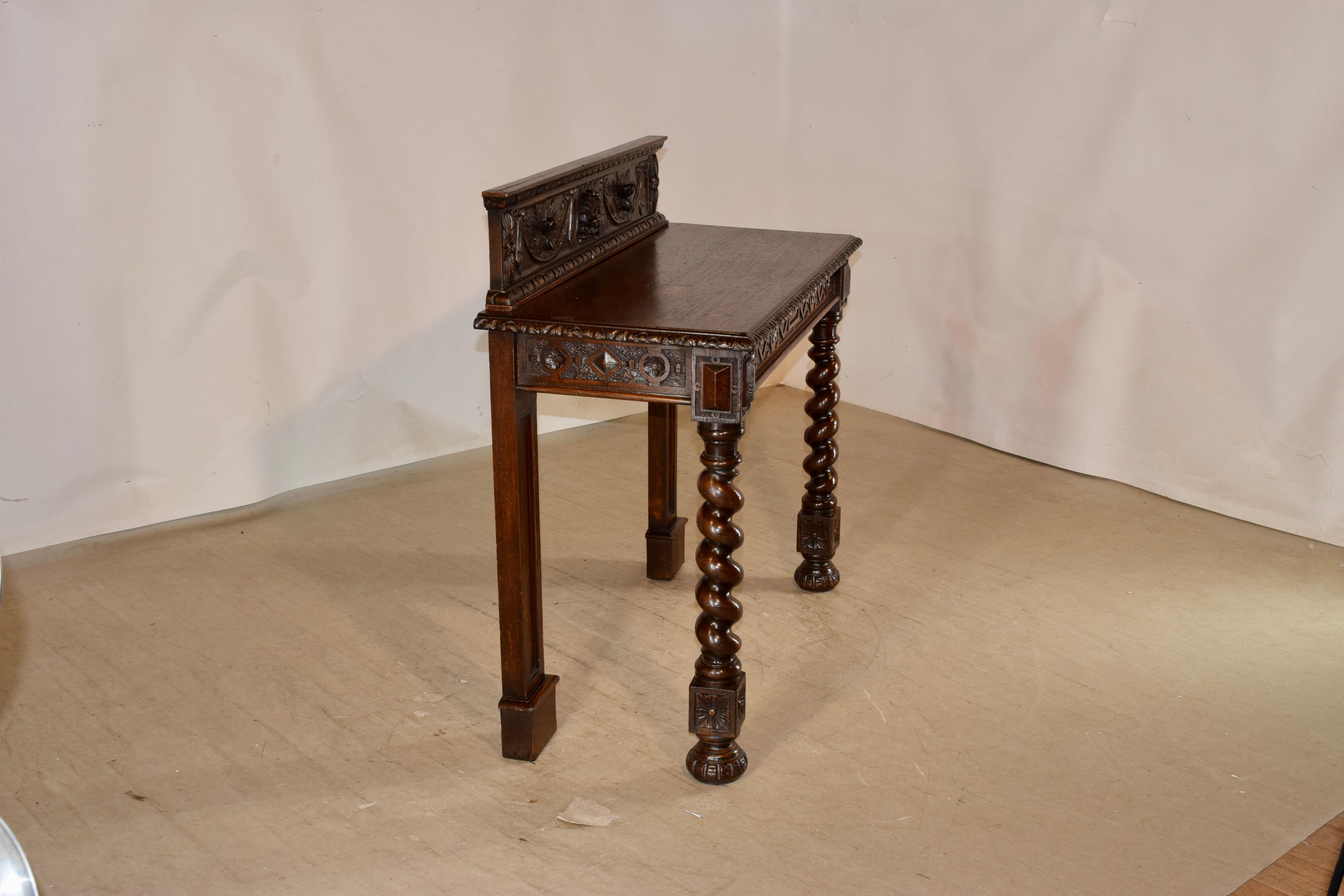 19th century English oak console table with exquisite carving. The table is signed Edwards and Roberts Wardour St London. Edwards and Roberts were one of the premier English furniture makers in the 19th century. the backsplash is expertly hand