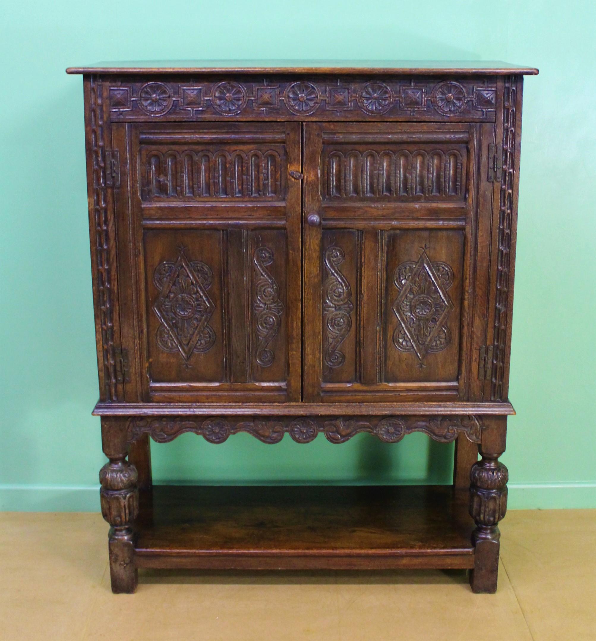 A solid oak 19th century carved oak cupboard of generous proportions. Of paneled construction with a pair of doors which open to access a shelved interior. With carved decorations and standing on turned baluster legs, united by an under-tier.