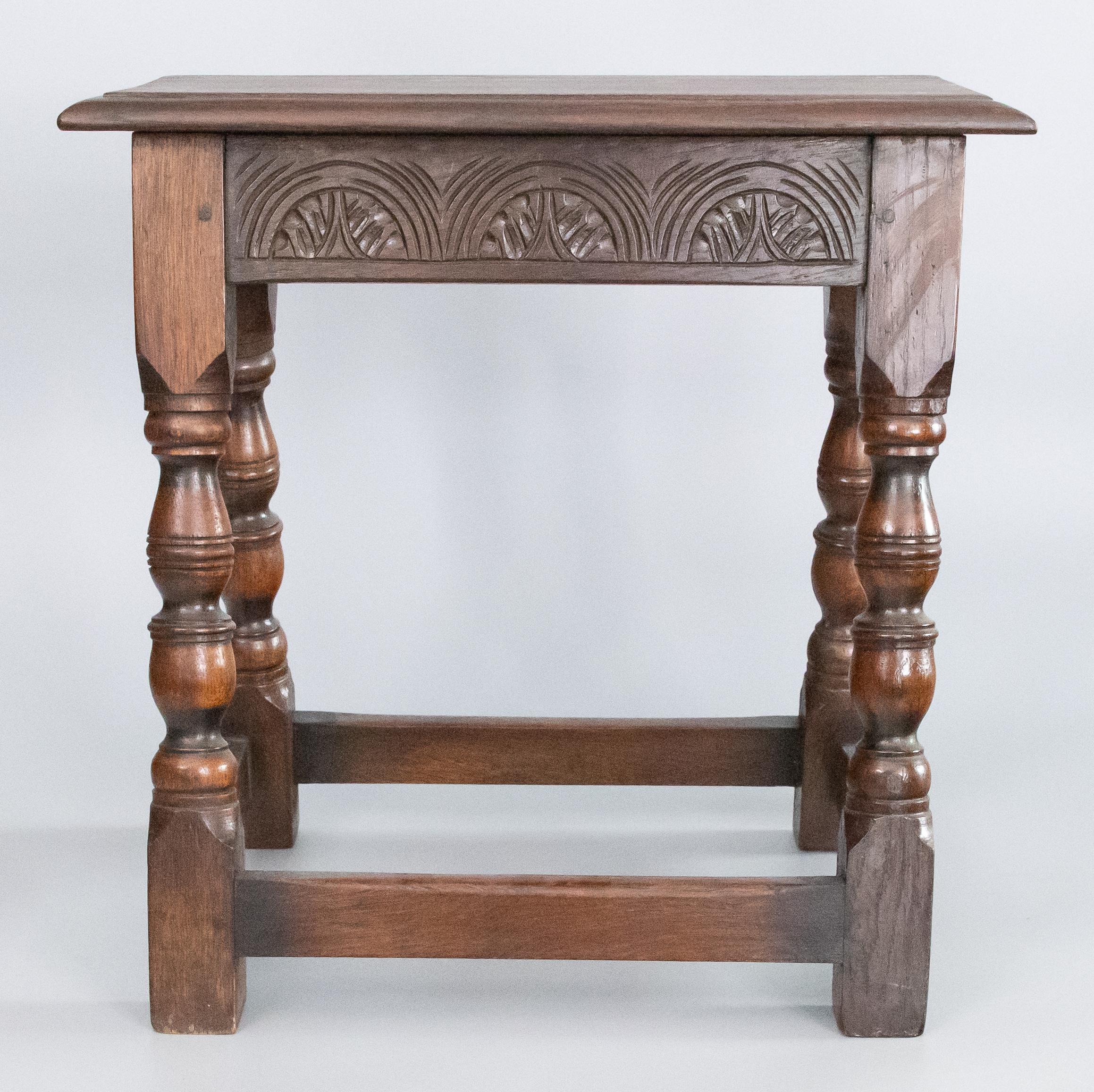 A superb antique 19th-century English oak joint stool with a beautifully carved apron, hand turned legs, and beveled seat. This fine stool would be great for extra seating and also perfect as a side table for beverages or your favorite