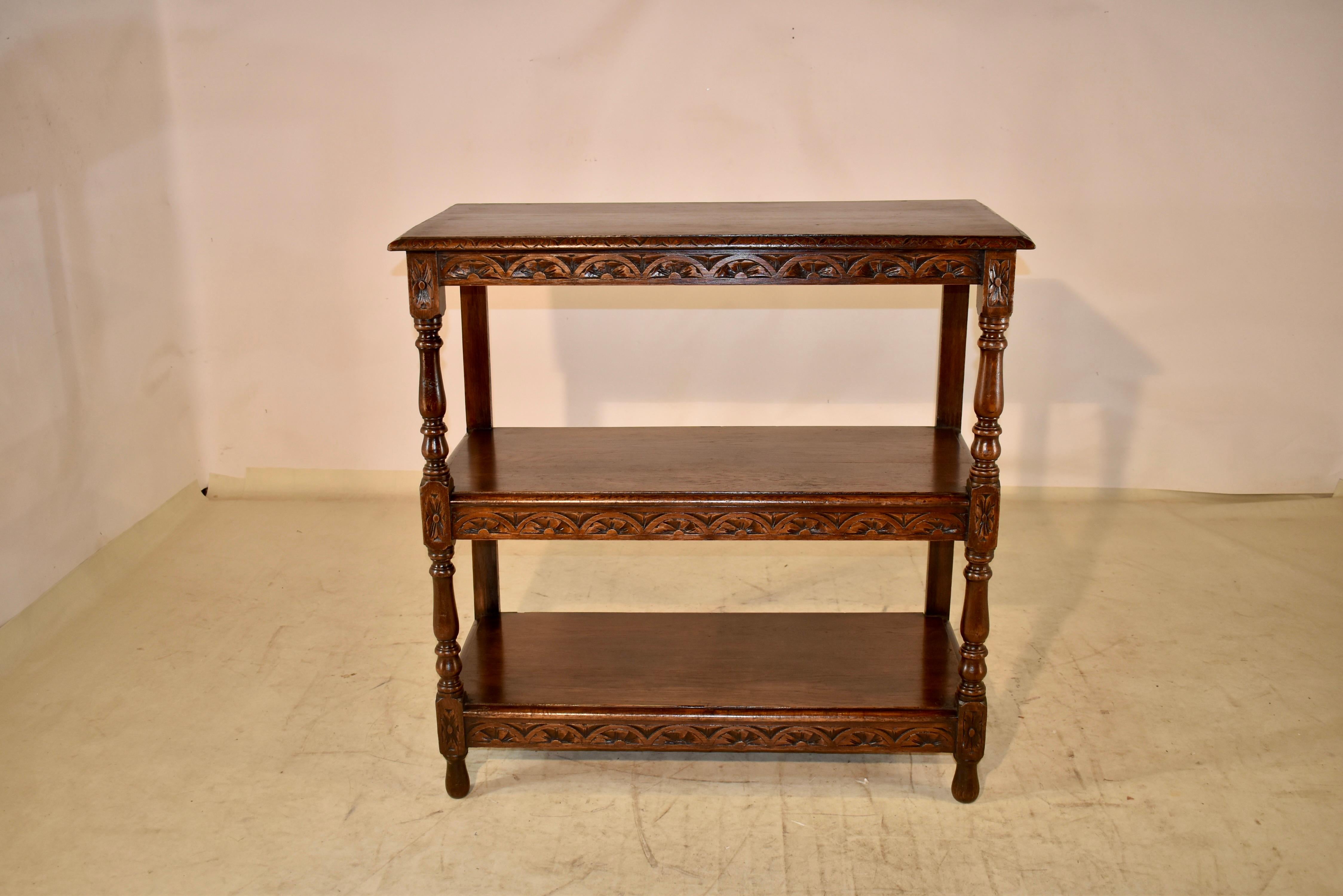 19th century carved oak shelf from England. The top has a beveled edge, following down to hand carve decorated shelf supports beneath the top and two lower shelves. The shelves are separated by hand turned shelf supports in the front and simple legs