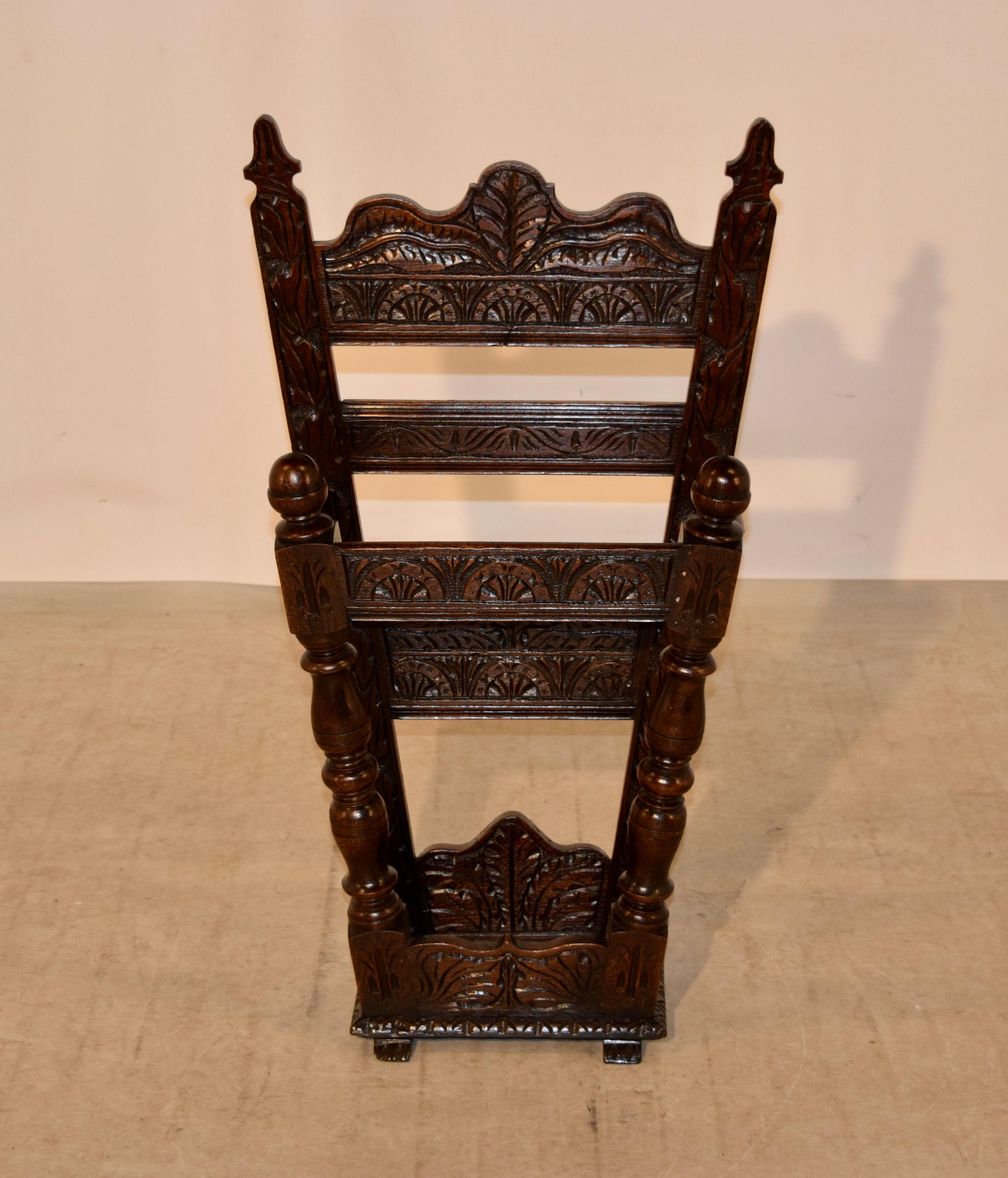 19th century oak hand carved stick stand from England. The back is splayed and is expertly hand carved with lovely decoration and the front is made up of hand-turned legs, also splayed, and joined by hand carved rails to the top and by a tray on the