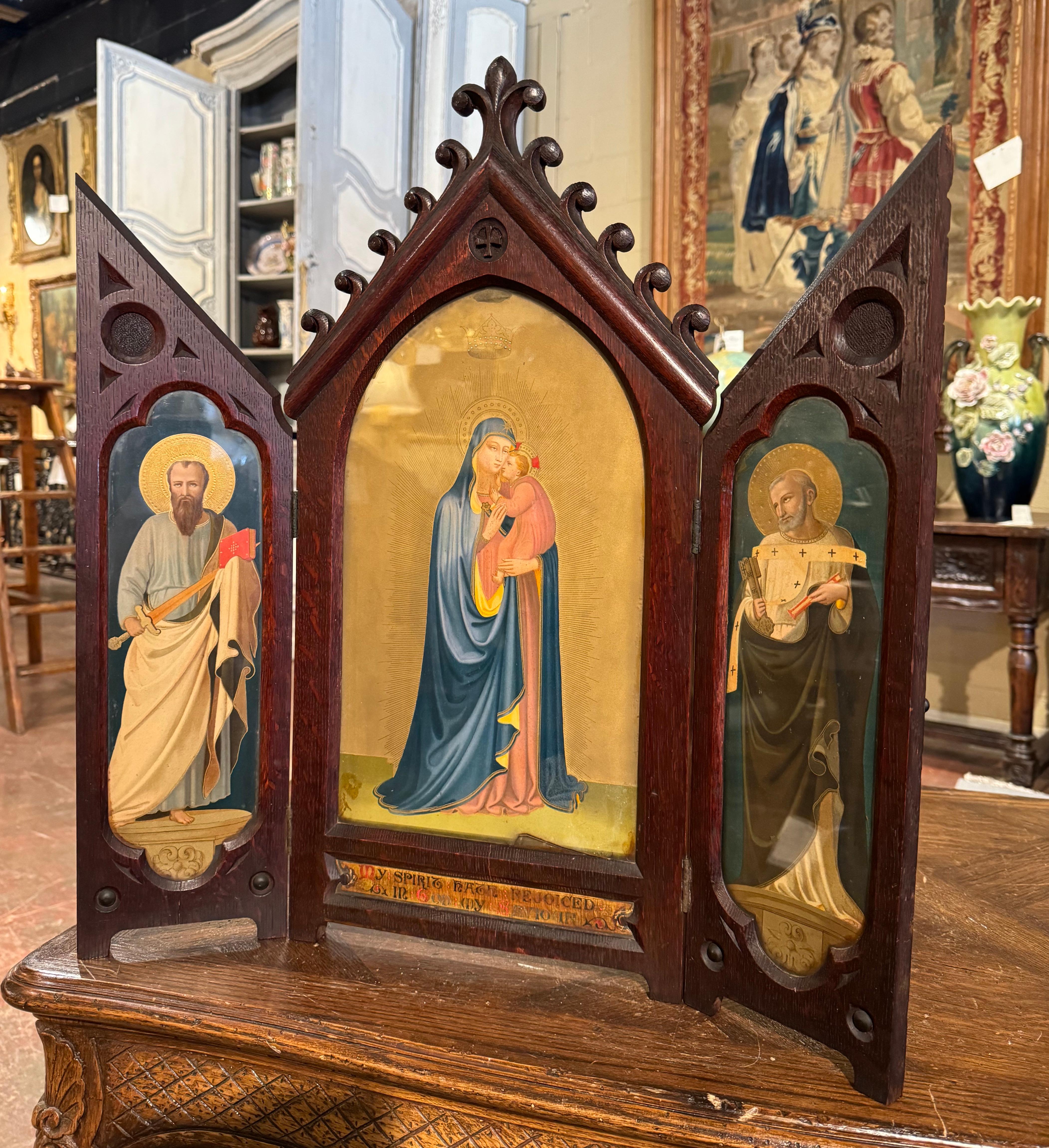 Place this antique Gothic triptych on a table for your daily devotions! Created in England circa 1860, and made of oak, the religious work of art is built in three panels hinged together which can be folded shut or displayed open, and decorated with