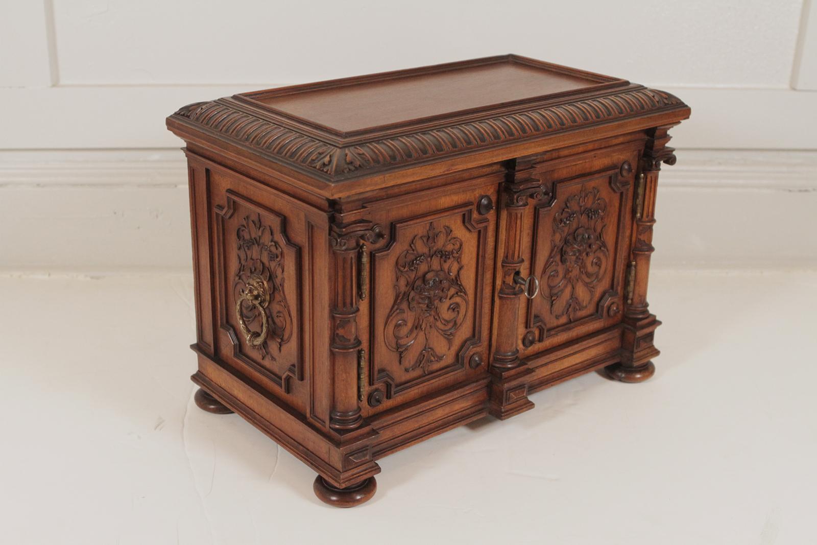 Extraordinary carved walnut two-door diminutive chest. The beautiful hand-carved case with two front doors depicting the lord of the winds on the front and back. The box has finely cast brass ring and lion handles on both sides. The doors open to