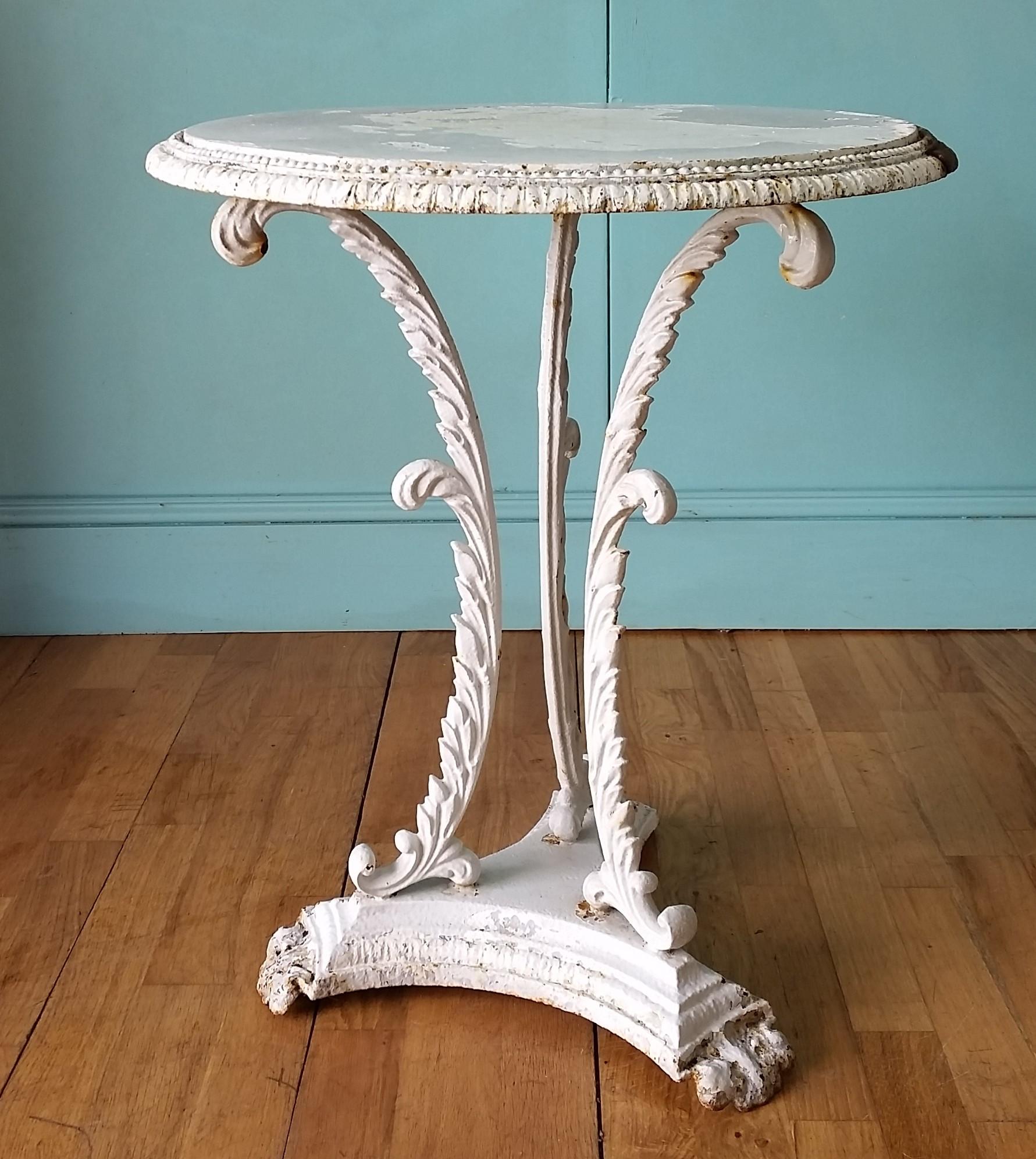 Antique English cast iron side table circa 1850 - 1880's
Decorative trifold base with acanthus leaves and lion paw feet with original iron table top.
Antique white paint finish has worn from exposure to the elements to produce a lovely authentic