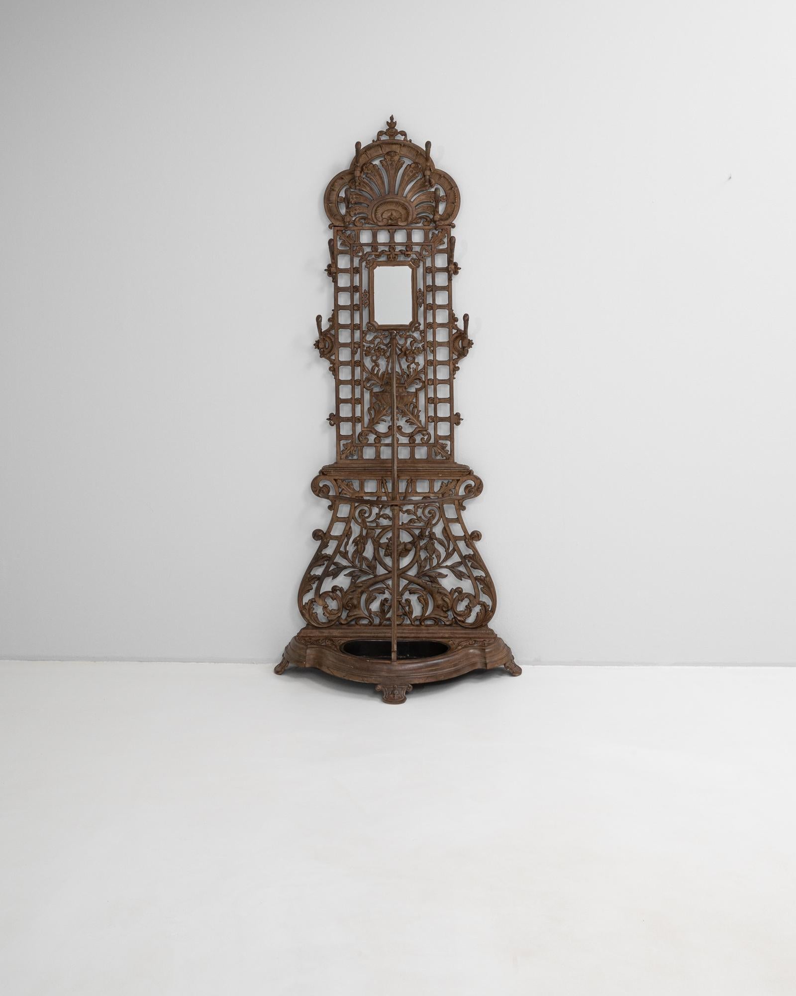 This 19th Century English cast iron hall stand is a richly detailed example of Victorian design, combining elegance with utility. Crafted in an intricate openwork lattice pattern, it features elaborate scrollwork, stylized foliage, and a shell crest