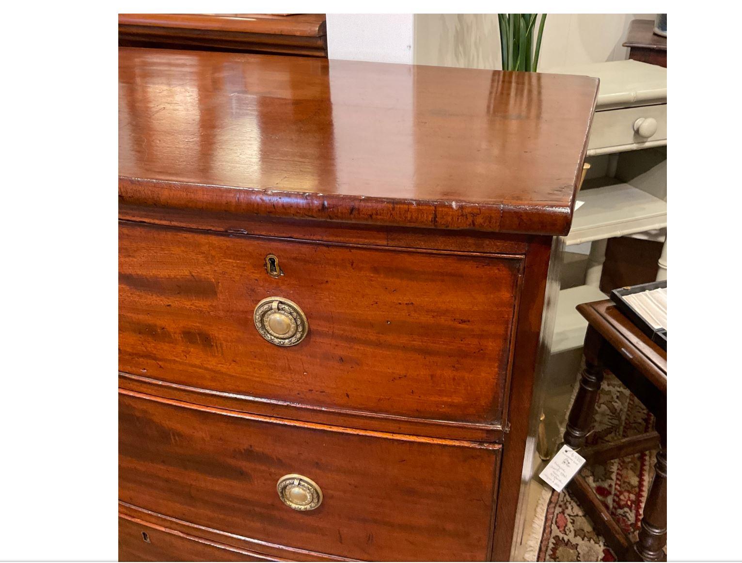 This is a beautiful 19th century English chest! The walnut wood is glossy and has nice natural design. This piece is two over two with a bowfront that is accented with brass pulls with delicate hand carved detailing. This chest is a great