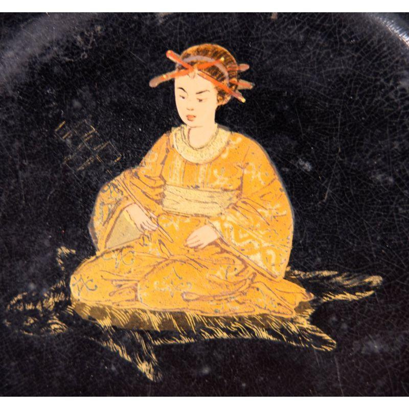 An antique 19th-Century English black lacquered papier mache wine coaster or tray with a handpainted Chinoiseirie figure and gilt edge. It would be beautiful for display, added to a collection, or for serving.

 