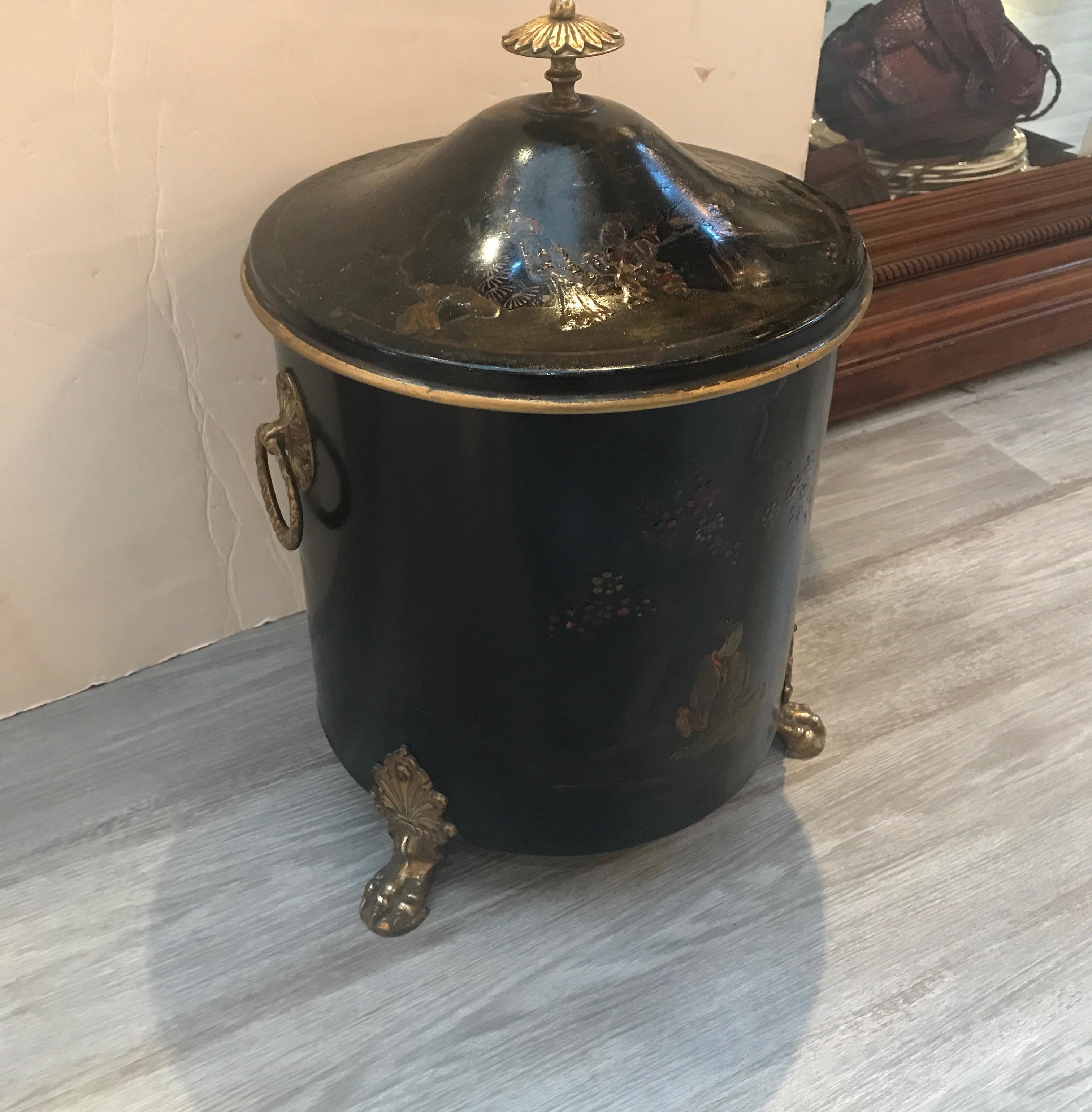 A round tole-ware chinoiserie Tinder box for small logs or kindling. The black background with Asian inspired decoration all around. The handles, finial top and feet in cast brass. Being over 100 years old this box has some wear but in overall well