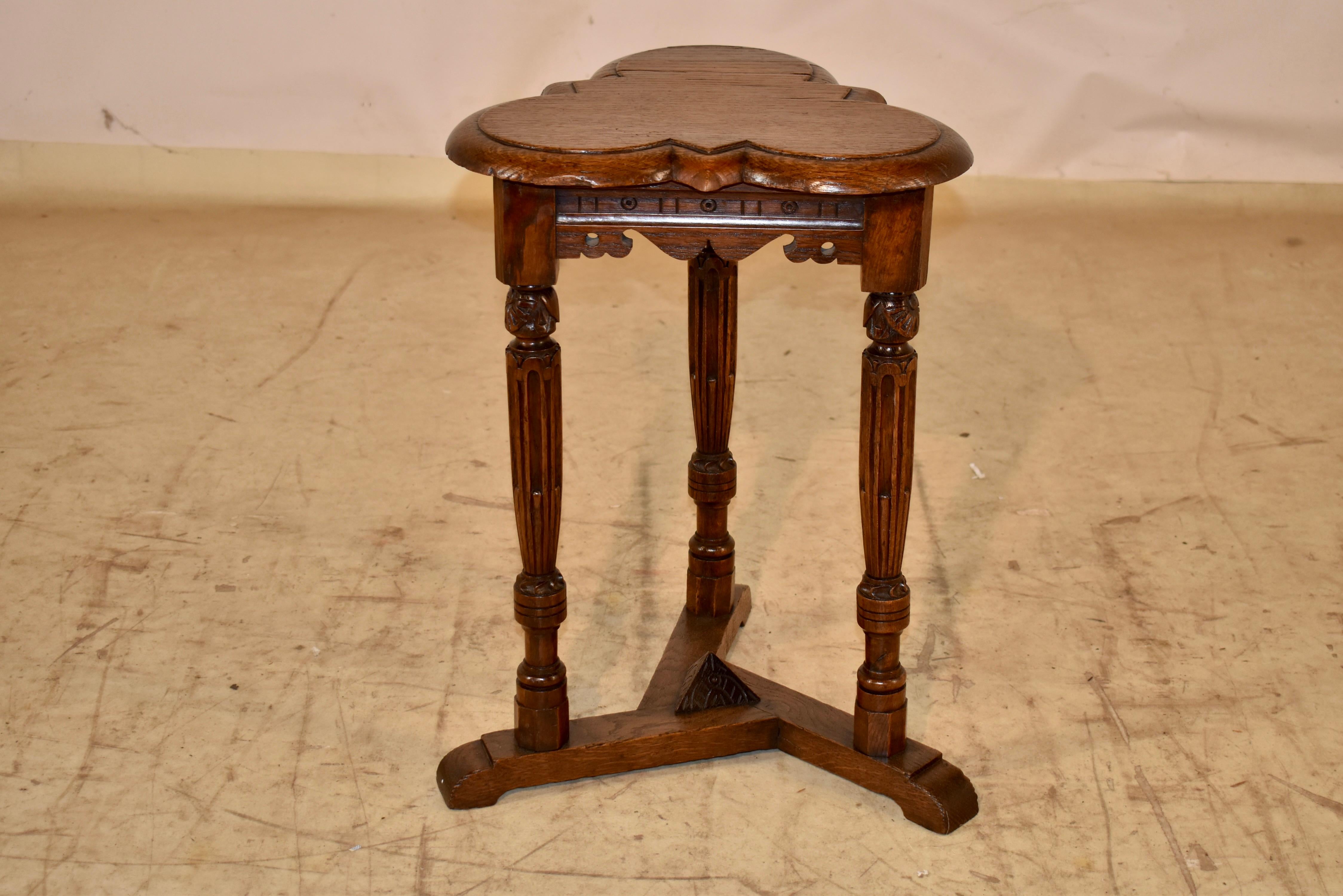 19th century English oak side table with a clover shaped top. 

The top  is beveled and scalloped around the edge , following down to scalloped and decorated aprons on all three sides, for easy placement in any room. 

The legs are expertly hand