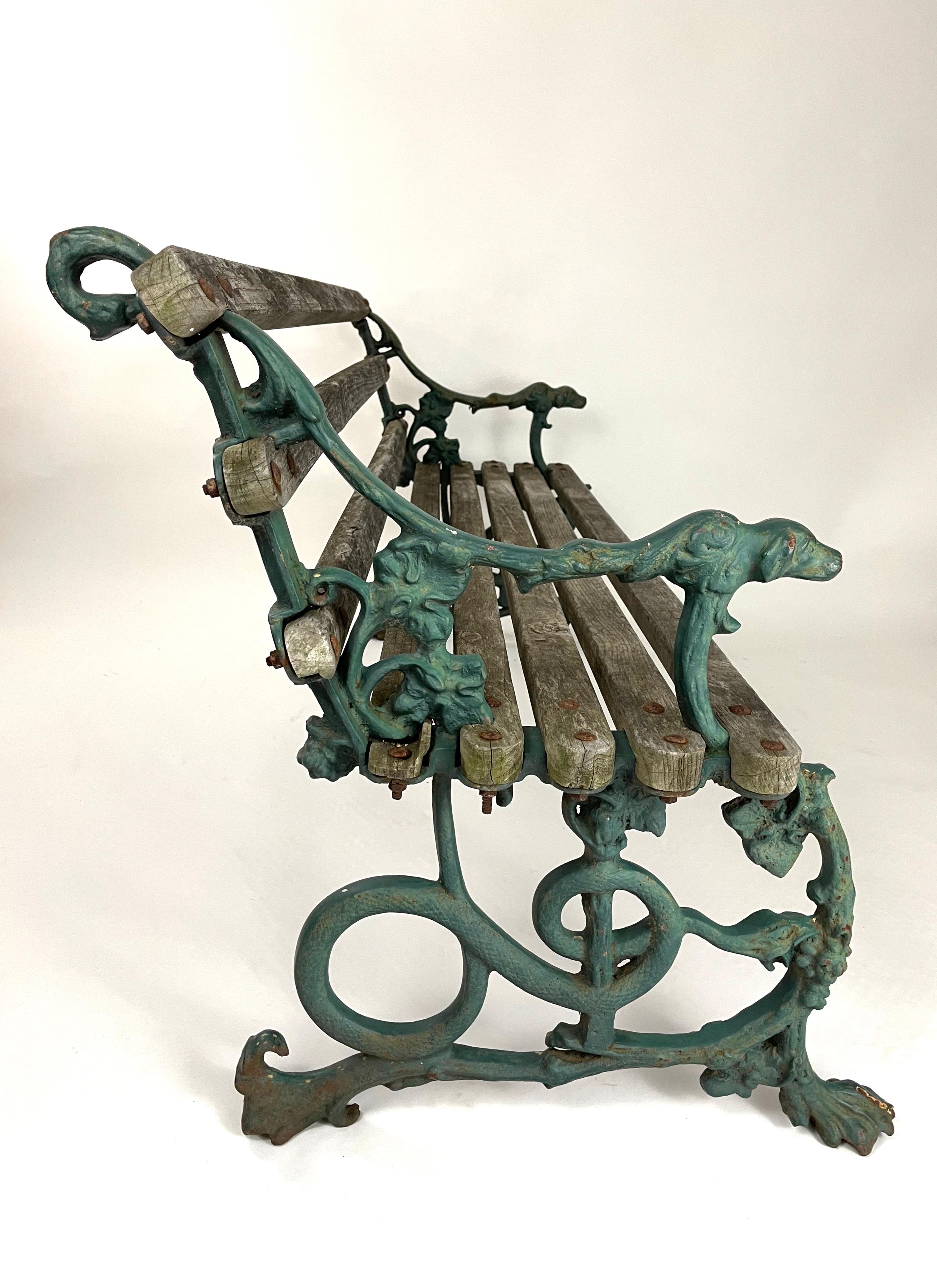 A beautifully designed and very comfortable 19th century English cast iron garden bench by the celebrated Colebrookdale foundry, with very solid and nicely weathered oak slats at just the right angle, flanked by whimsically designed, green painted