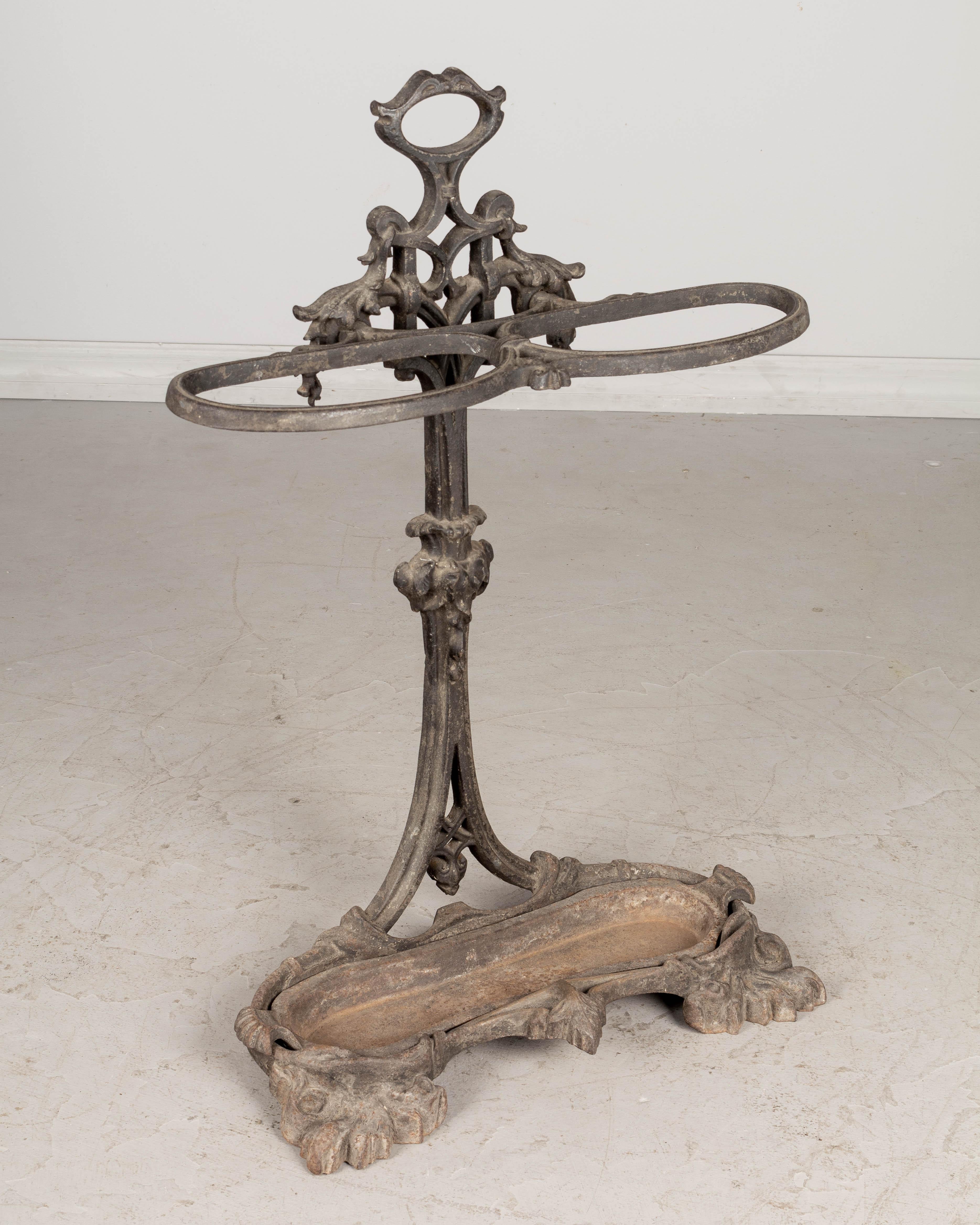 A 19th century English cast iron umbrella stand with faded black painted finish with rusty patina. Detailed iron work with oval loops to hold the umbrellas upright and a removable drip tray. Foundry stamp under drip tray: Coalbrookdale. Weight: 30
