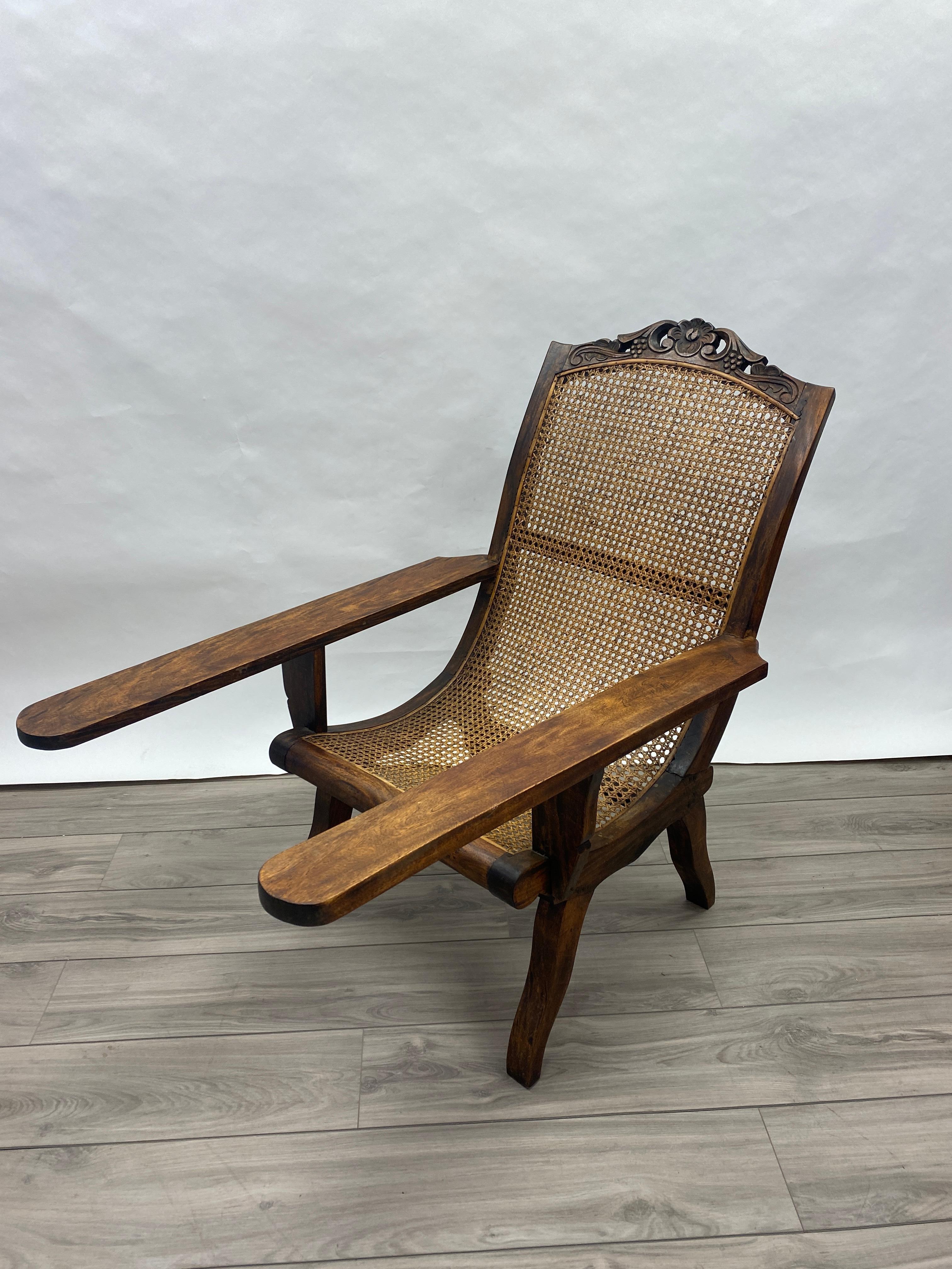 A sturdy and well made English colonial teak planation chair with original cain and stationary arms. Very nice example of a late 19th century planation chair. Slight warping in the back but very solid and does not rock.