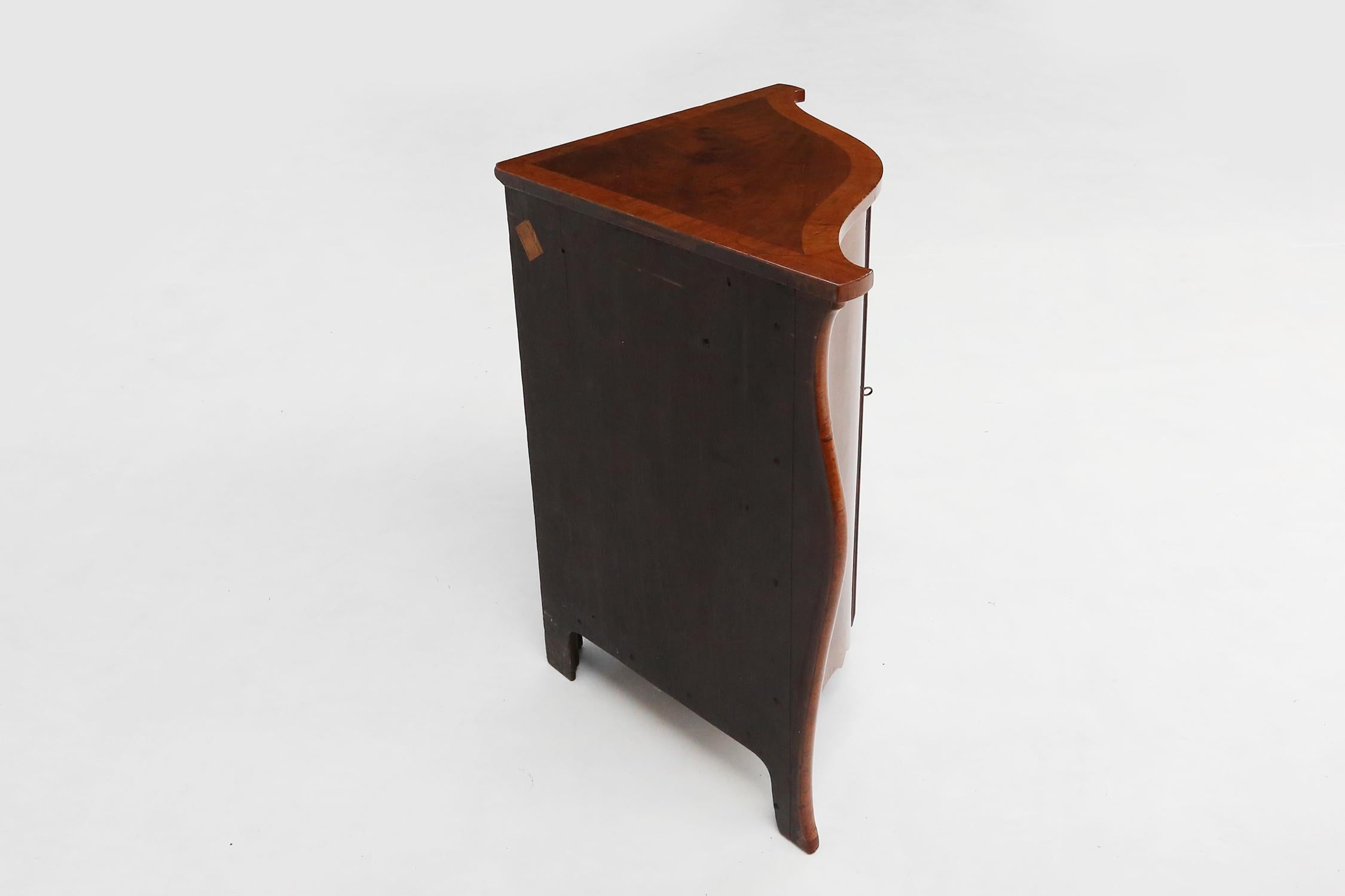 
This corner cabinet is made of wood and has a curved front, giving it an elegant and charming look. The corner cabinet has two doors with a keyhole in the middle, so you can safely store your belongings. The corner cabinet has a wooden top with a