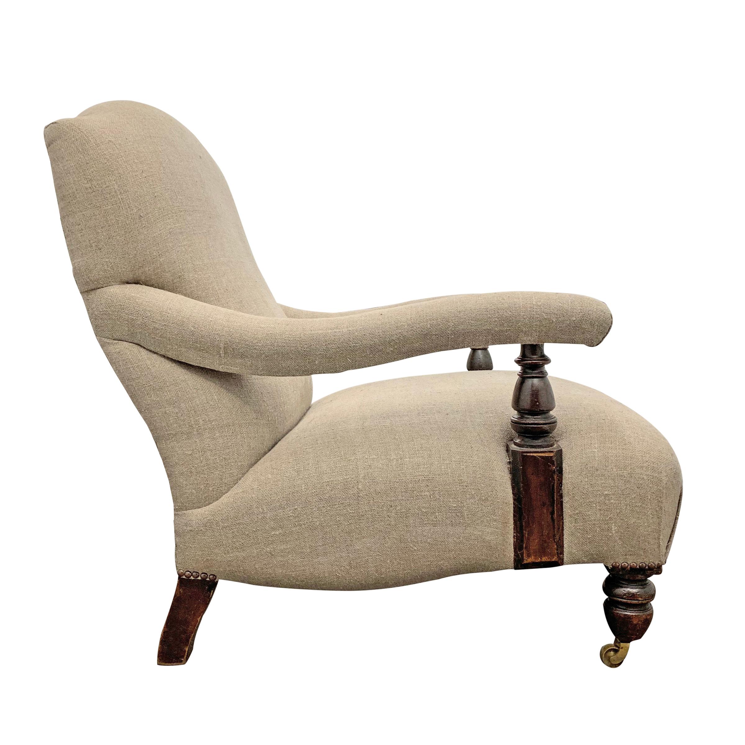 A comfortable 19th century English country house armchair with gently curved arms, newly upholstered in a heavy linen with a re-sprung seat, and short turned wood legs with brass casters on the front two legs.