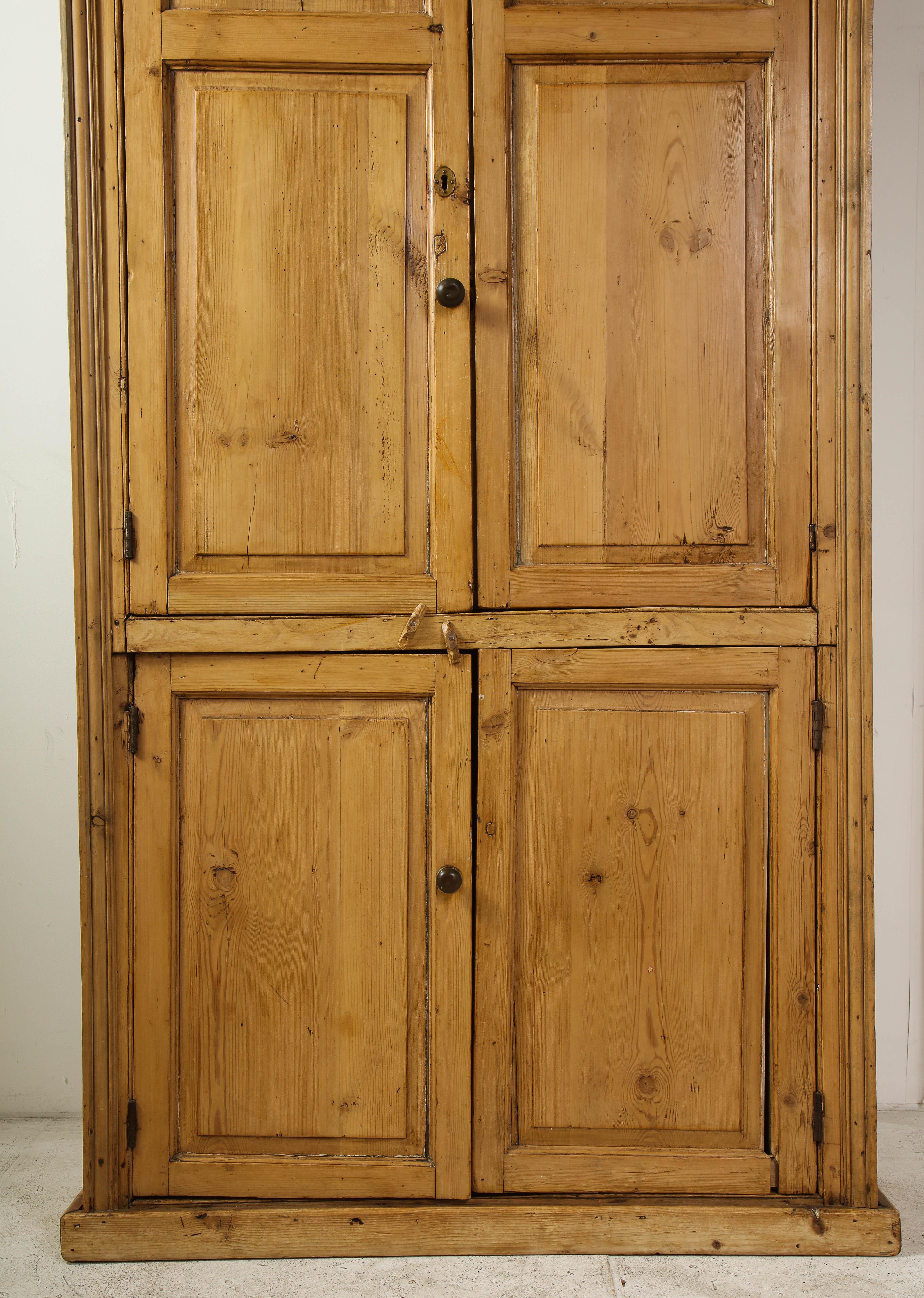 19th century English country pine bookcase with original hardware. One shelf in upper portion. Doors close easily.