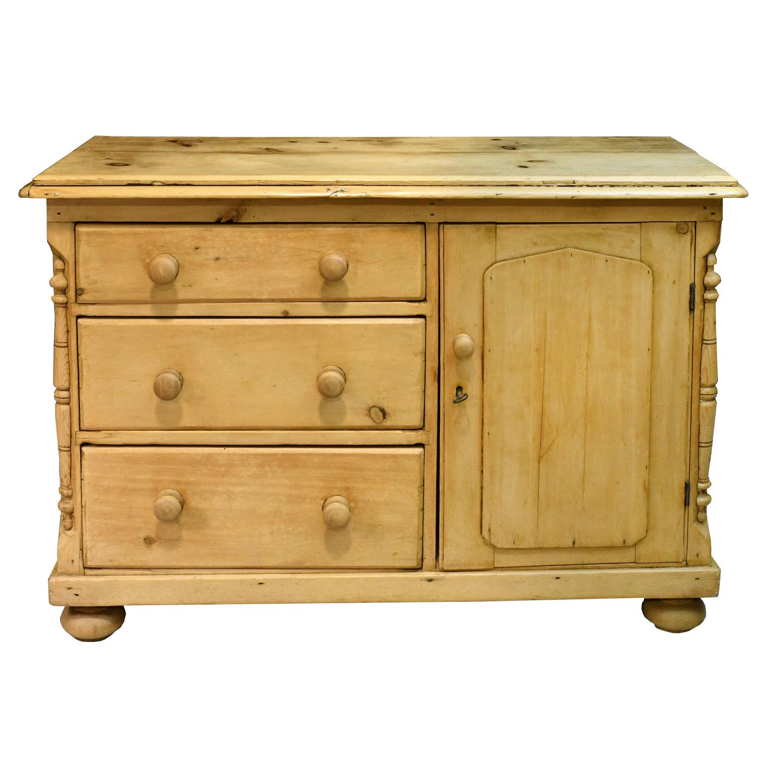 A charming English country dresser in natural, light-colored pine with a flight of three drawers and a cupboard, all with turned wooden pulls, lock and key. Cabinet rests on turned bun feet and has turned decorative elements embellishing the
