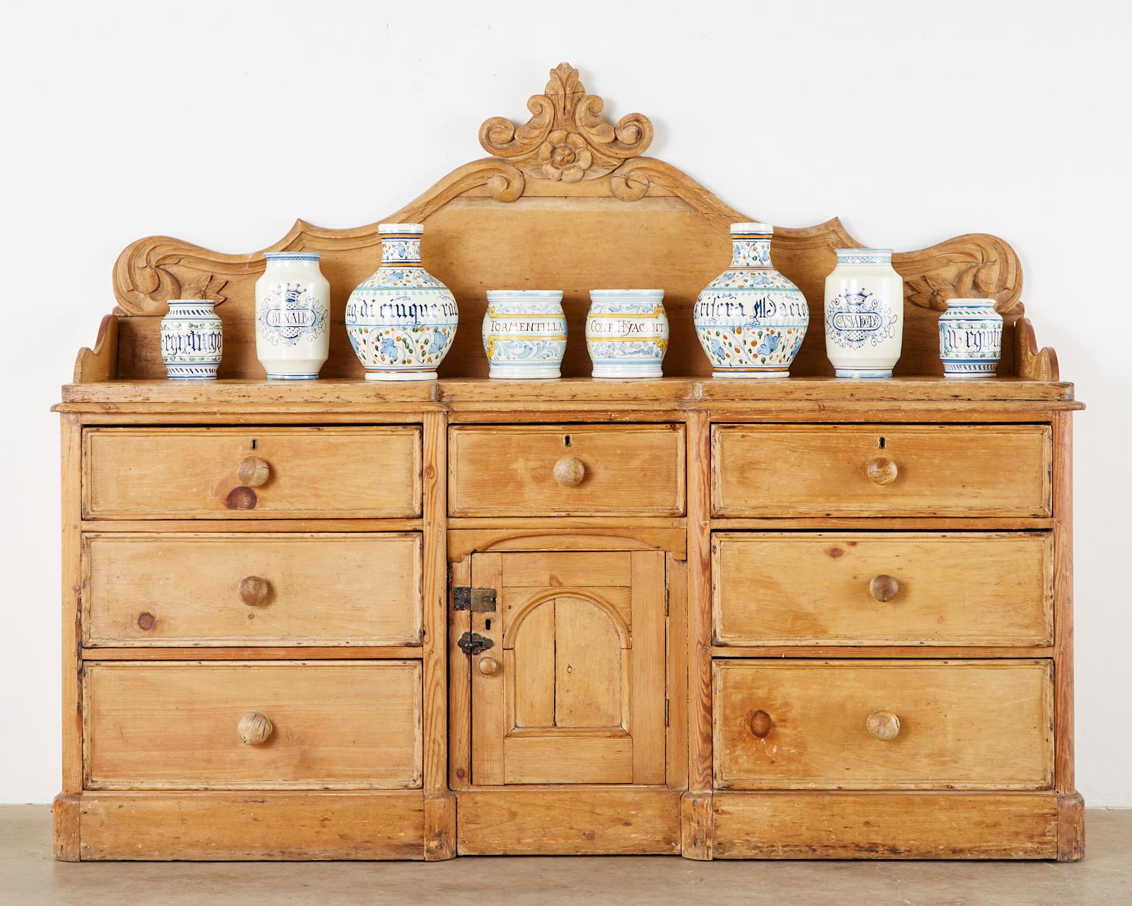 Rustic 19th century English country sideboard server or buffet constructed from aged thick pine. Features galleried sides and a grand peaked backboard embellished with scrolled acanthus decoration and a center floral spray. The case is topped with a