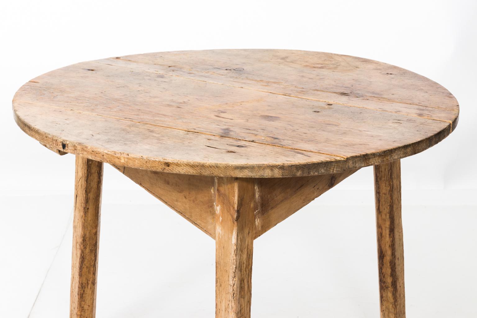 Round English pinewood cricket table supported by three triangular legs, circa 1870. Please note of wear consistent with age including surface scratches and dents that give the table a roughhewn finish.
 