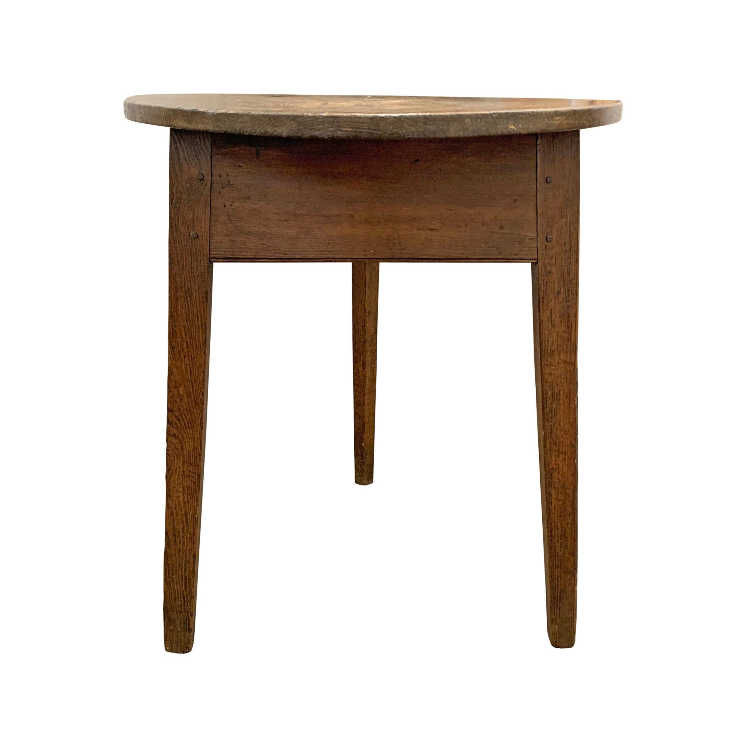A quaint early 19th century English pine cricket table with three tapered legs, a simple apron, and a solid pine top. A gorgeous old iron strap repair with hammered rivets is on one of the corners, and we think it's perfect!