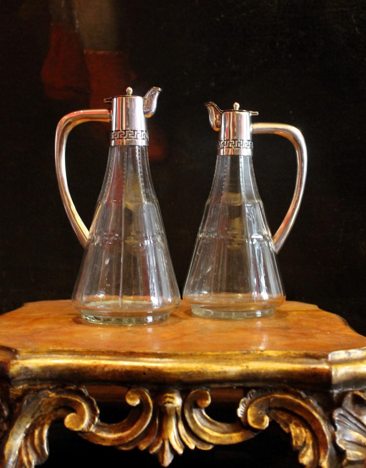 These oil and vinegar bottles are a sleek cruet condiment set, made of fine and elaborate cut crystal and sterling silver with a neoclassical appeal thanks to the Greek key pattern that never goes out of style
The glass bottles, cutted with