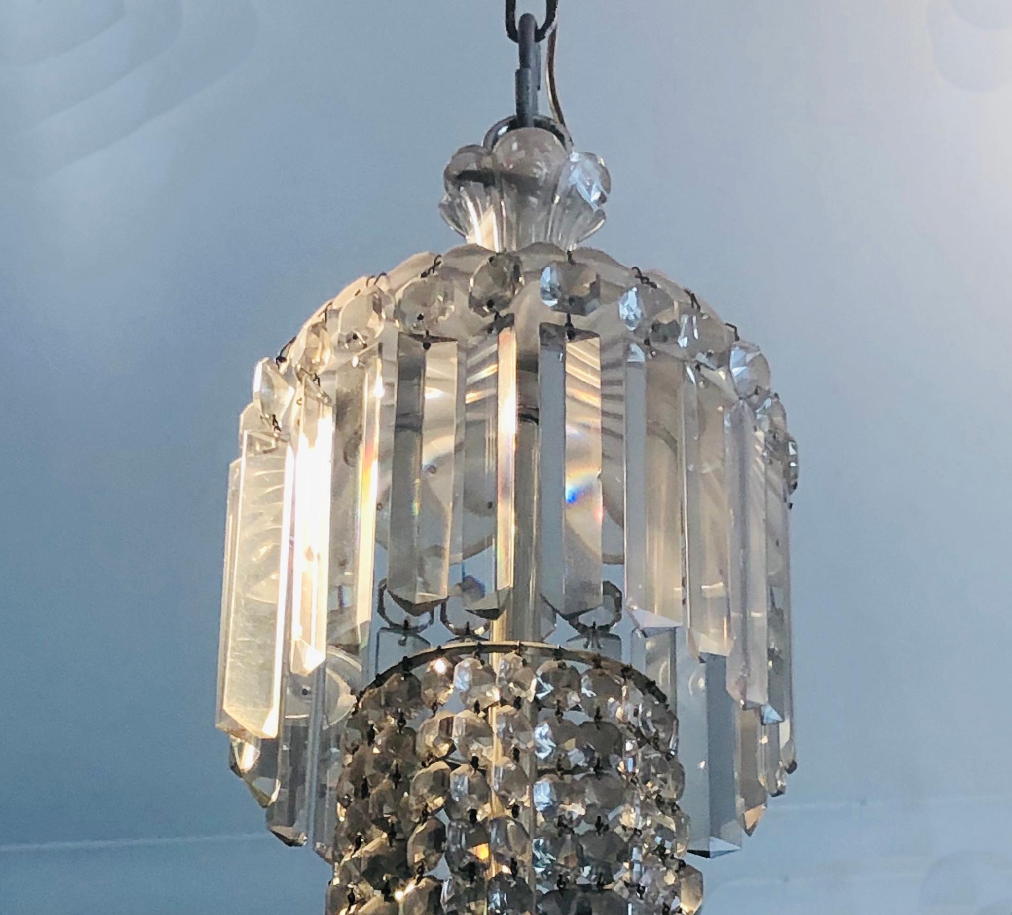 A large and impressive antique English cut-glass chandelier, having prism pendant canopy above graduated chains of double star prisms. The chandelier, fitted with six candle-arms with pendant drop lotus-shape cups above four prism-pendant