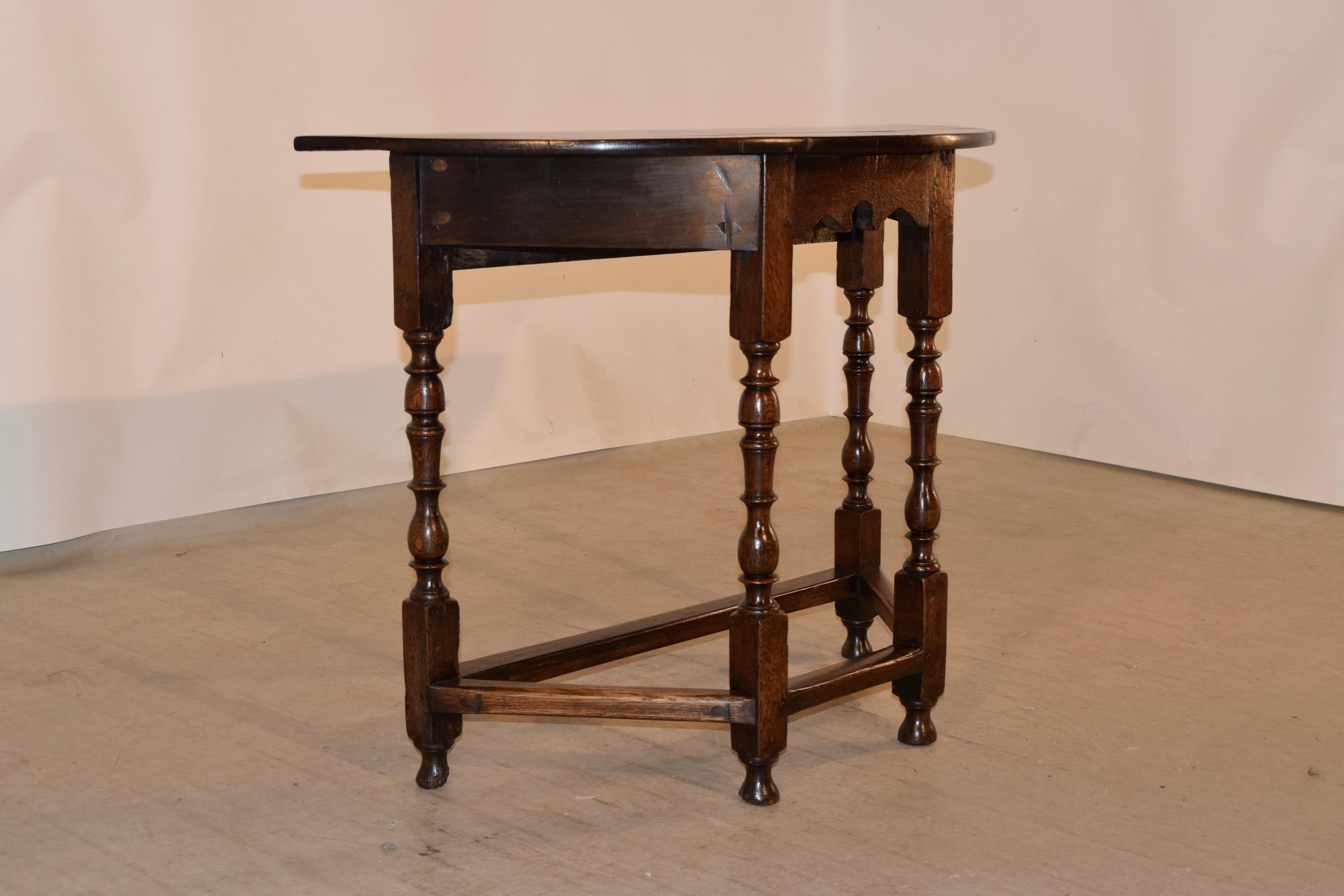 19th century oak demilune table from England. The top is made from planks and is pegged in construction, following down to a scalloped apron in the front and supported on wonderfully shaped hand turned legs, joined by simple stretchers and raised on