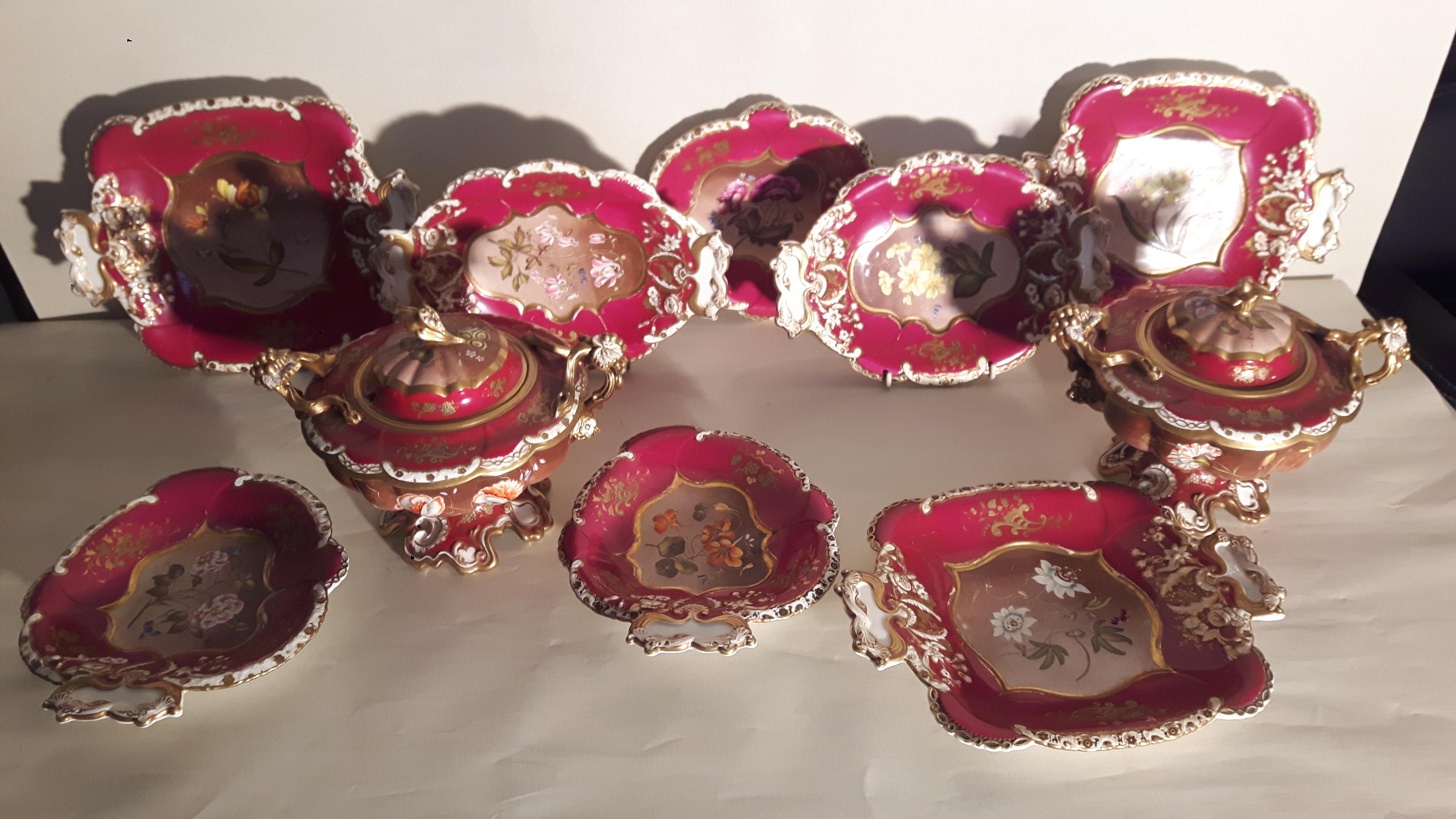 A very ornate burgundy red and gilt dessert service with lidded compotiers and serving plates, each piece hand-painted with a floral design on a painted backdrop .
The borders are embossed with white and gilt leaf designs, the all very highly