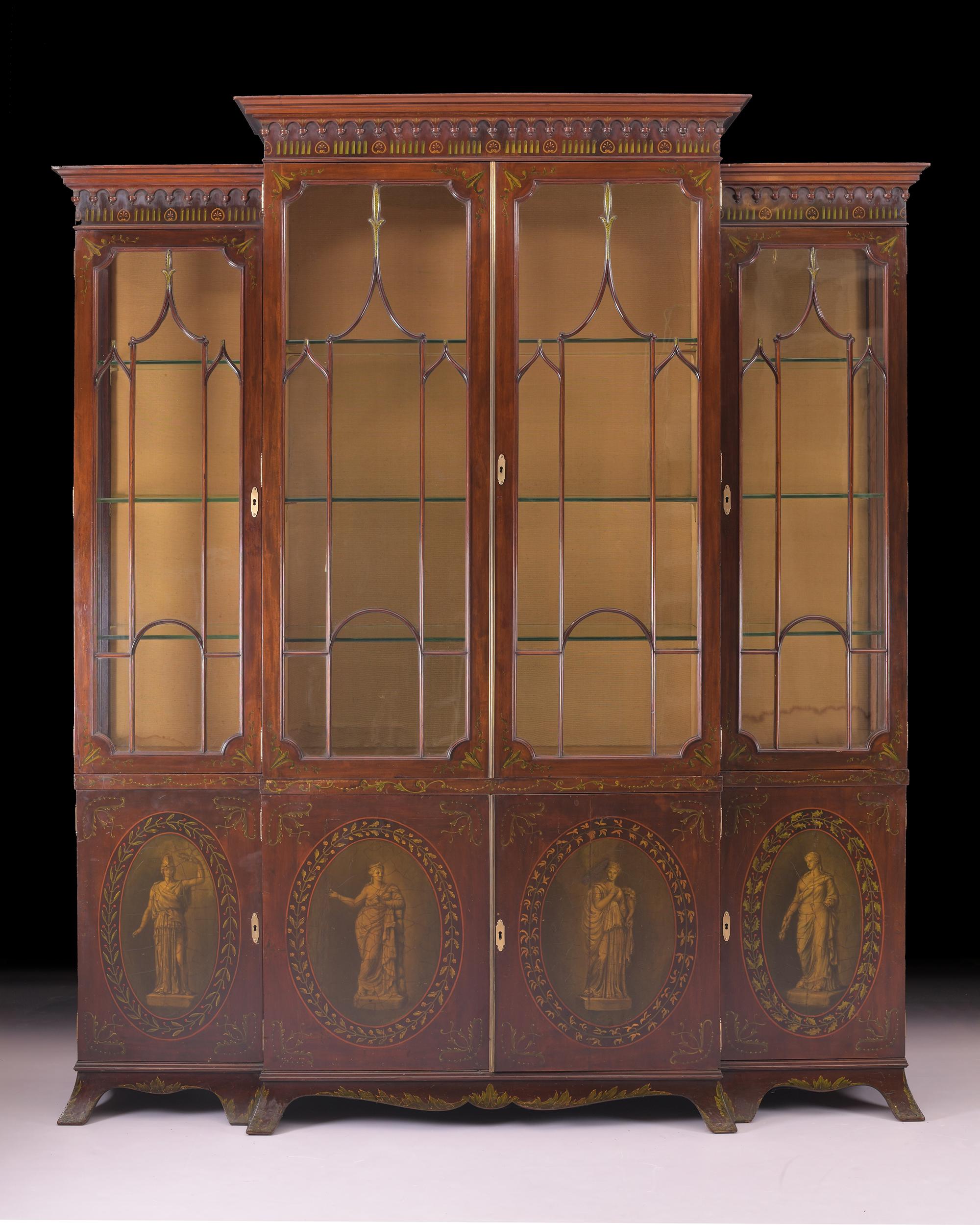 A late 19th century breakfront display cabinet. surmounted with pierced lattice work, cresting above four geometric glazed doors, with glass shelved interior over four fielded painted cupboard doors enclosing a shelve interior terminating on eight