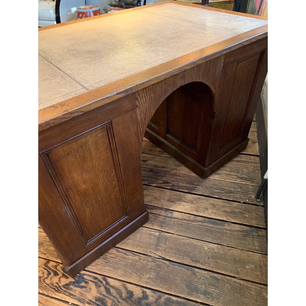Handsome English double pedestal desk with grain painted, paneled sides, arched front, and 4 drawers in each pedestal on one side. Tooled light tan leather top in good condition.
From the estate of a prominent New England decorator.

Measures: