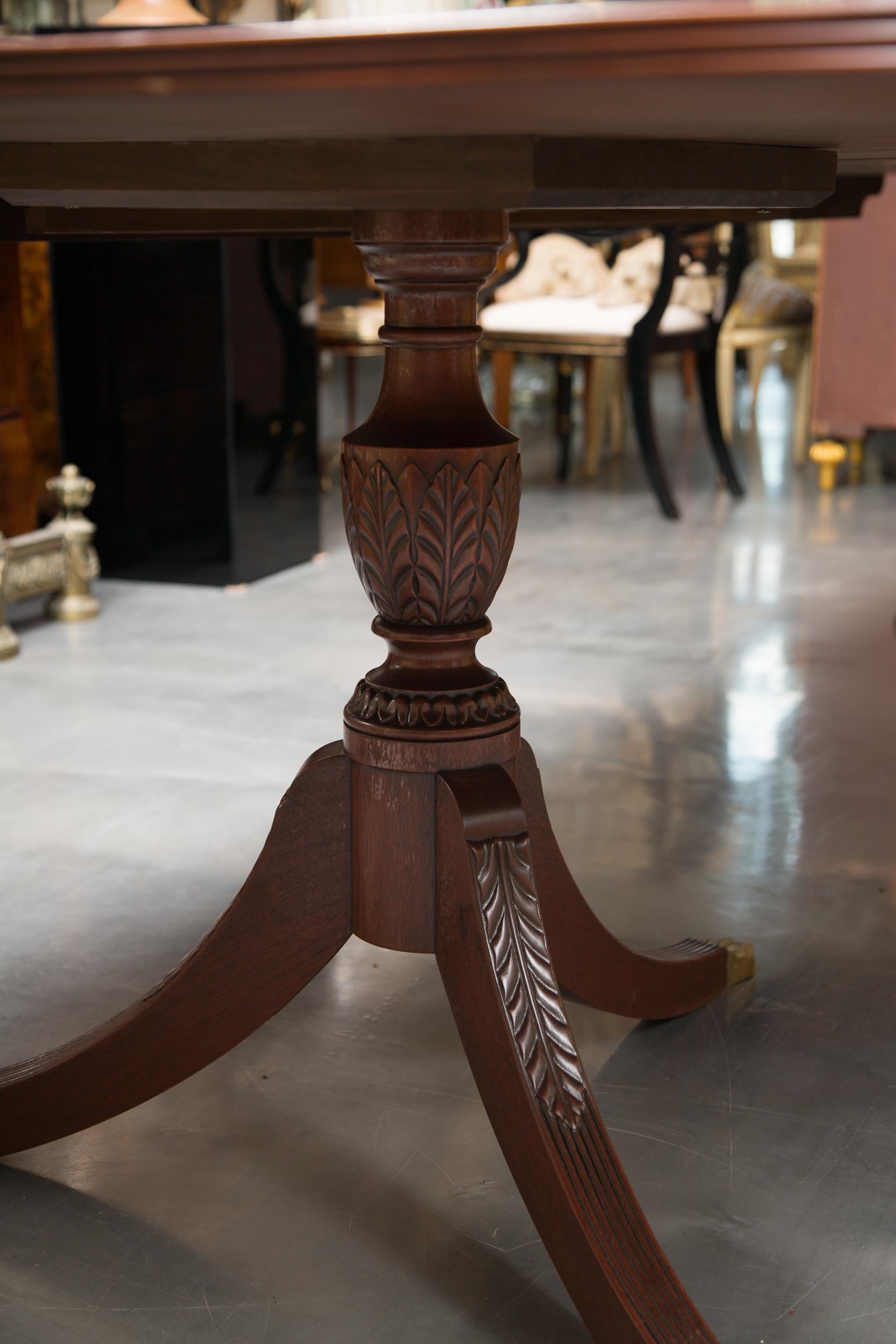 This is the perfect table for someone looking for a larger than normal dining table. This English George III style mahogany dining table with reeded edge is supported by two tripod pedestals. There are two leaves available for extension, late 19th