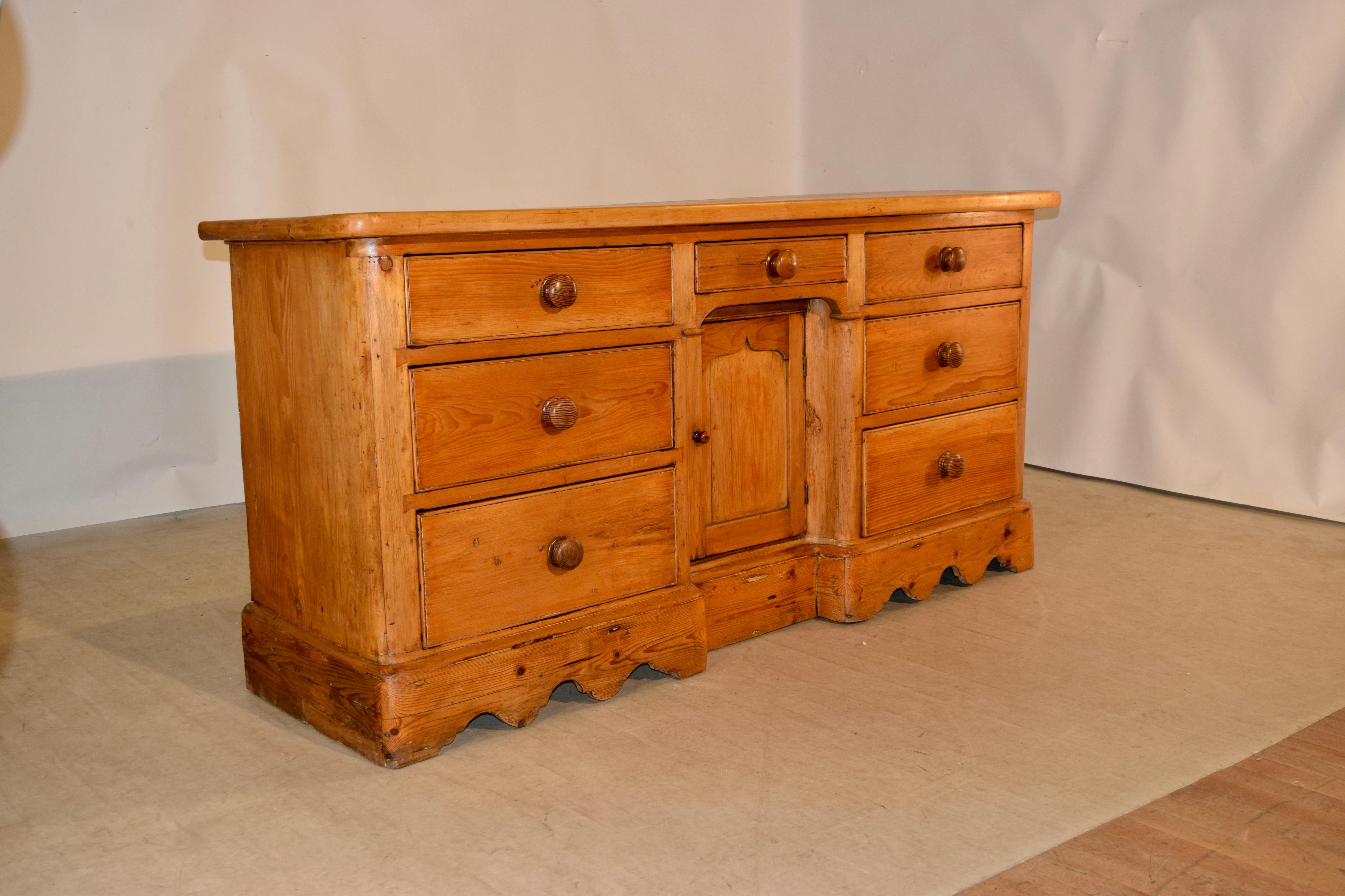 19th century English dresser base with a thick top made from sycamore which measures 1.5 inches in thickness. The base is made of pine and has simple sides and two sets of three drawers each flanking a single drawer over a single door which opens to