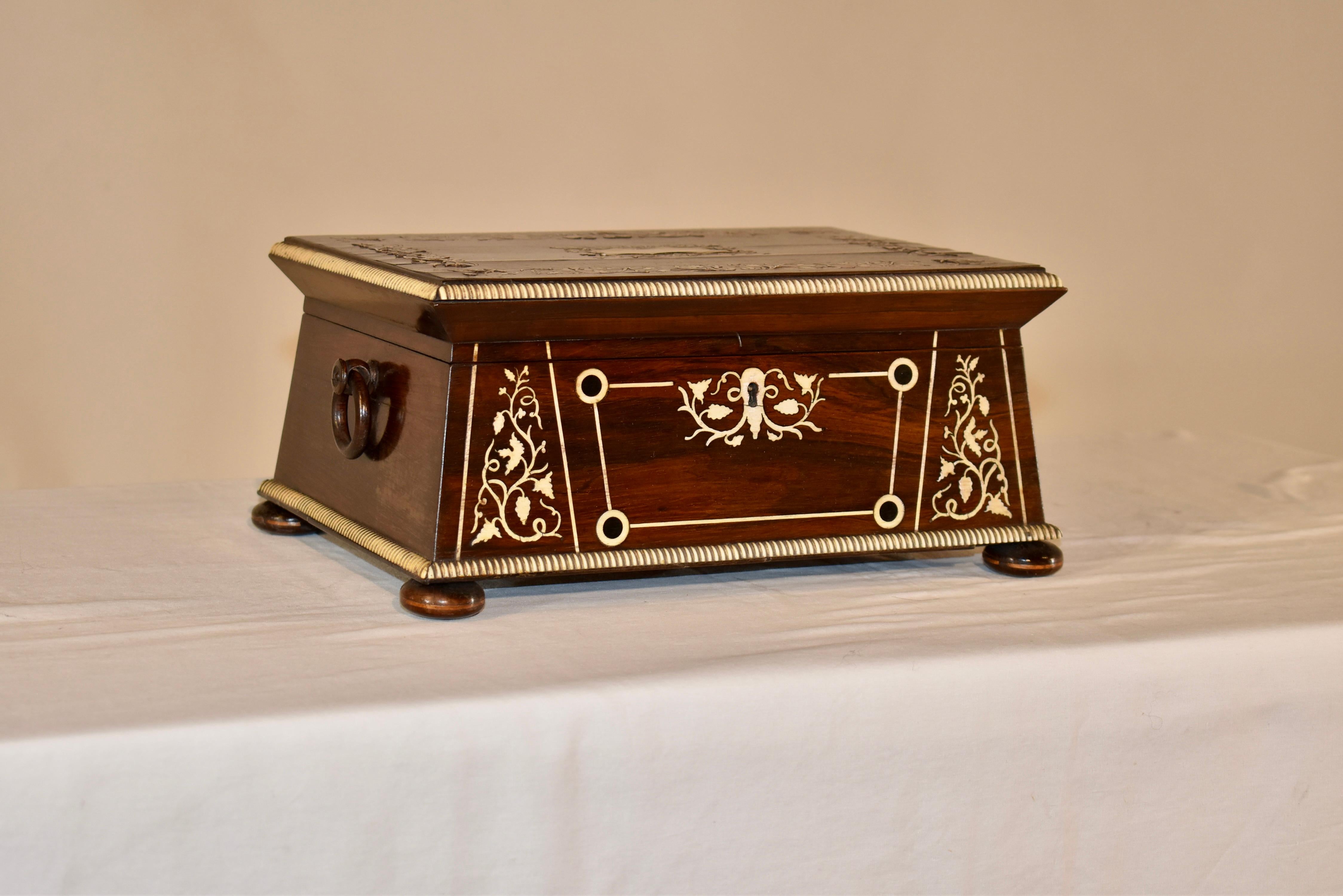 19th century English dresser box made from exquisitely grained rosewood.  The box has wonderfully inlaid patterns on the top and front in ivory, along with the beaded ivory trim.  There are two handles on either side of the box, and the box is