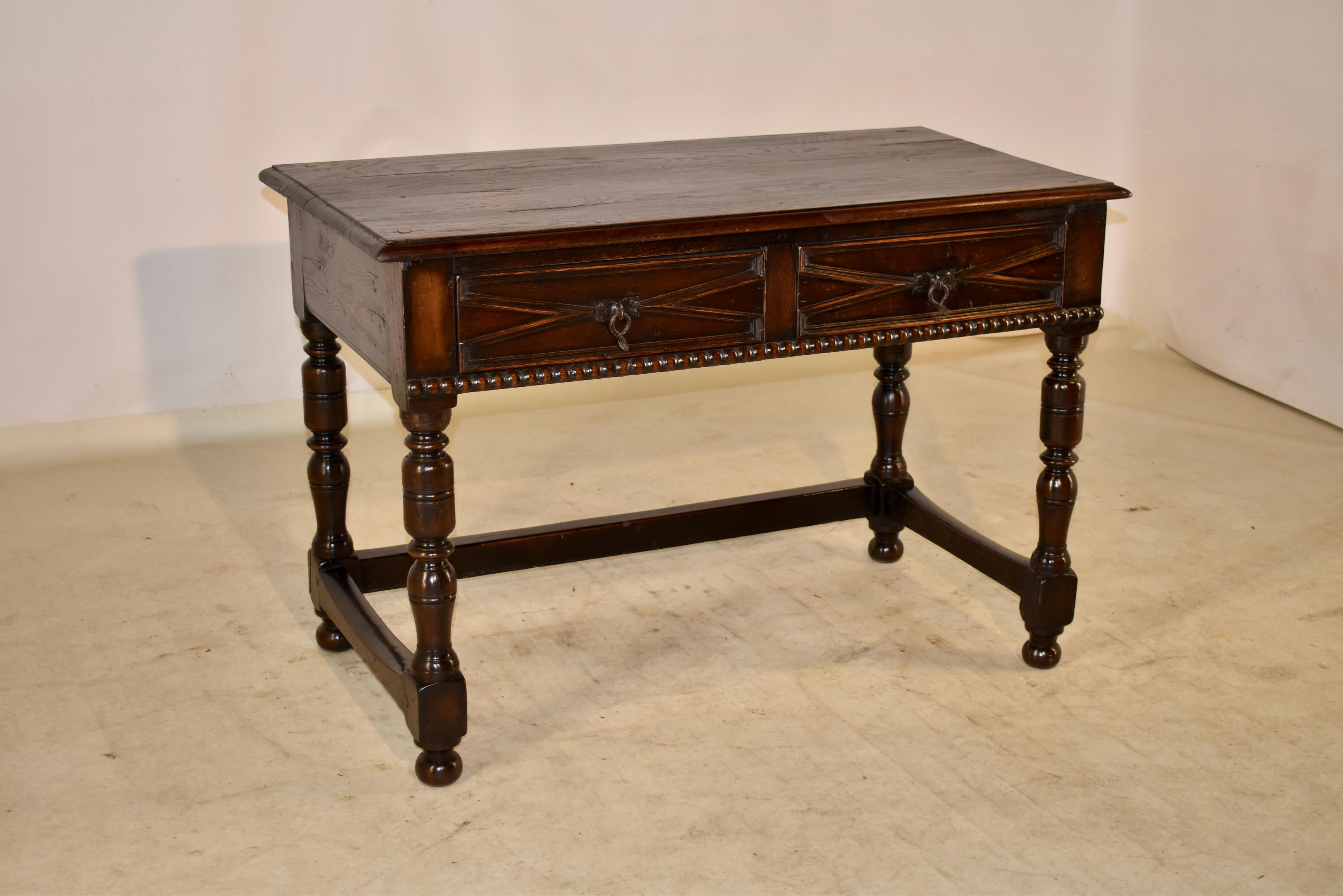 19th century elm and oak writing table from England with a lovely grained elm top which has a beveled edge, following down to elm sides, which also have rich graining. The front of the table retains two original drawers with the most charming hand