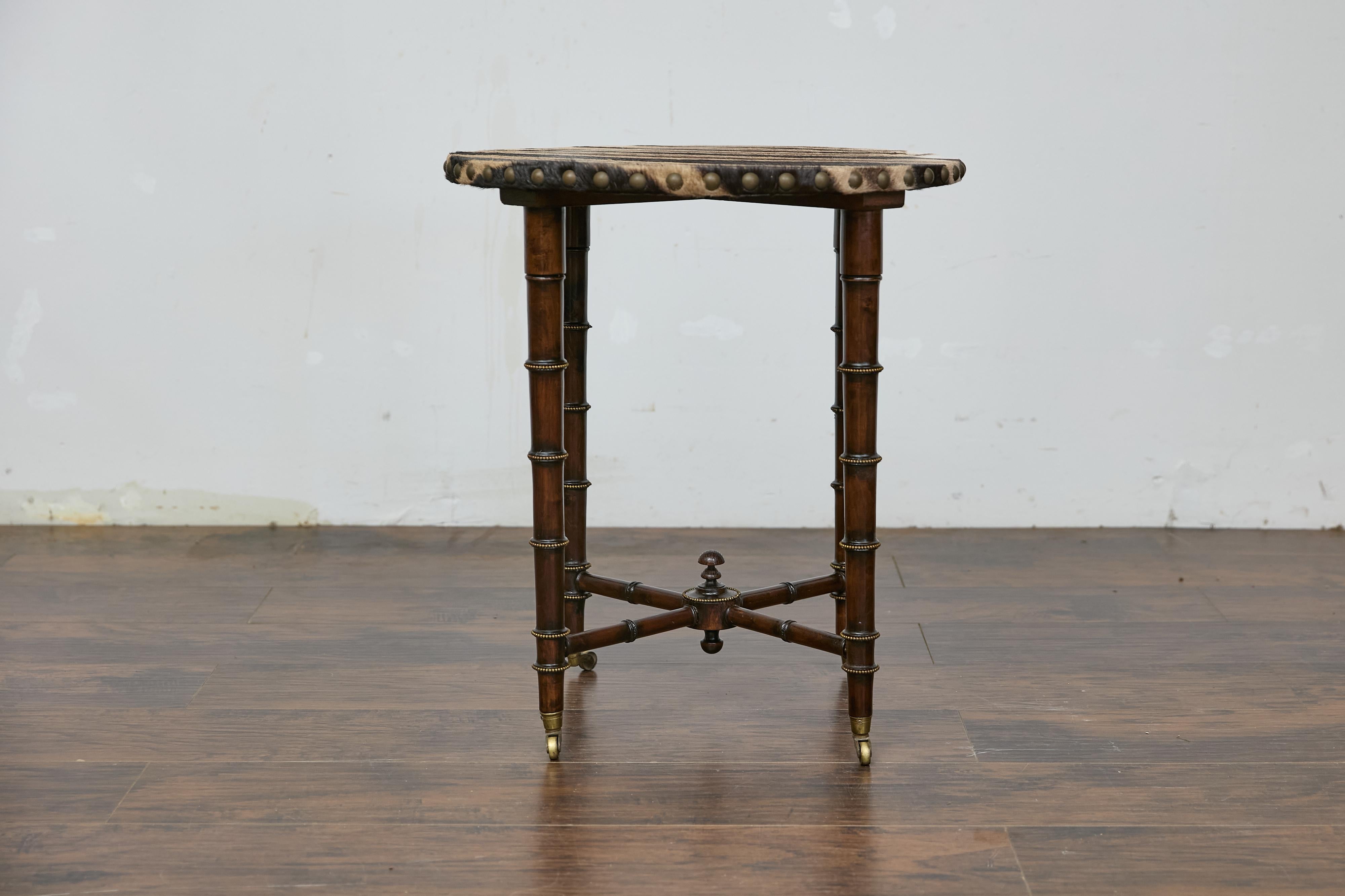 An English faux bamboo side table from the 19th century with faux bamboo base, zebra hide top and X-Form cross stretcher. This English faux bamboo side table from the 19th century exudes timeless elegance with its unique combination of materials and