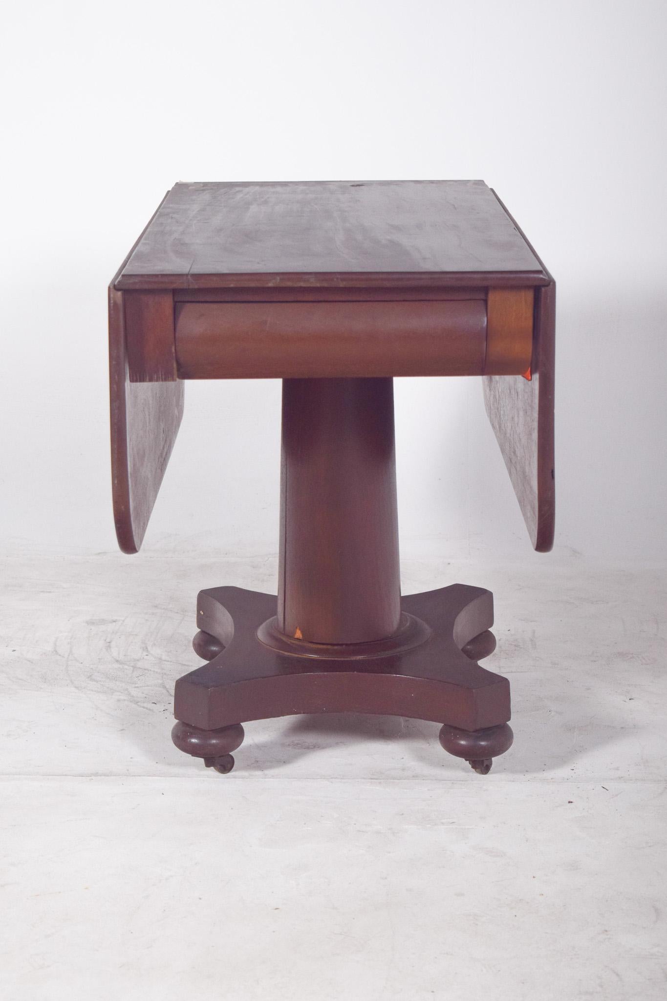 Flap table with central foot. The base is cross shaped with softly spherical wooden castors complementing the design with stability and light mobility. The folding side flaps make the top adaptable to different spaces and uses.
The dark wood finish