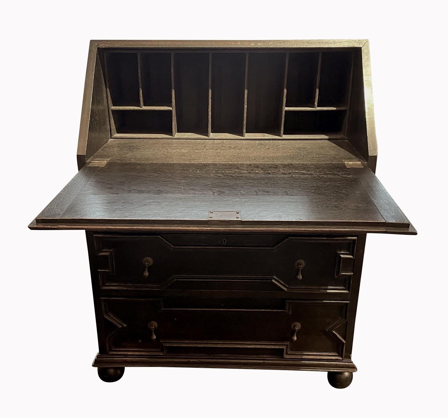 19th century English fold down desk / commode.
Ebonized oak finish.
Three drawers with brass pulls.
Multi cubbies for storage.
Decorative raised wood strip design.
Fold down desk is 29