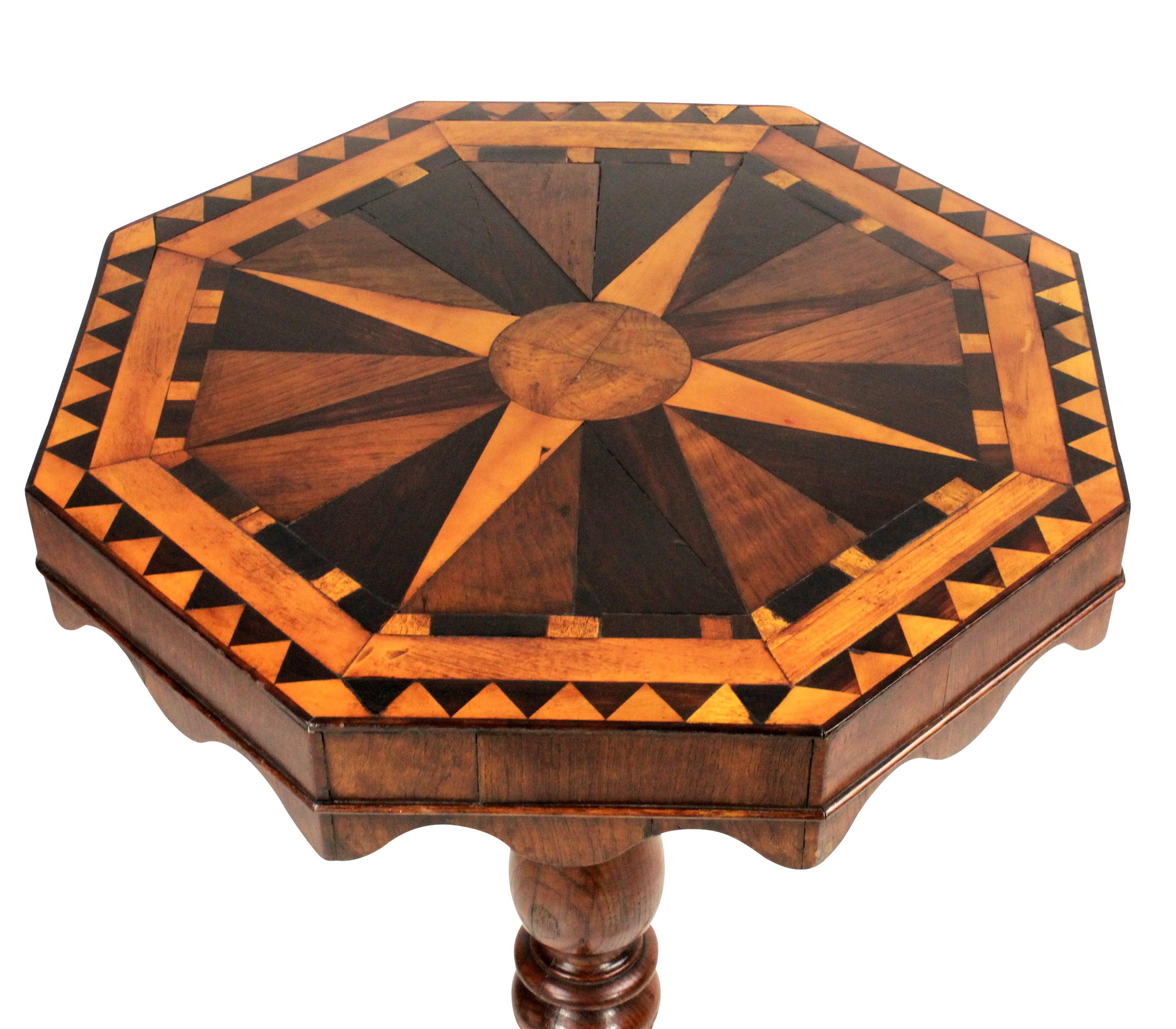 An English pedestal tilt-top table in elm with a fine geometric marquetry top in various English woods depicting a globe and compass. The turned tripod base supporting a tilt-top with scalloped apron with original latch.
 