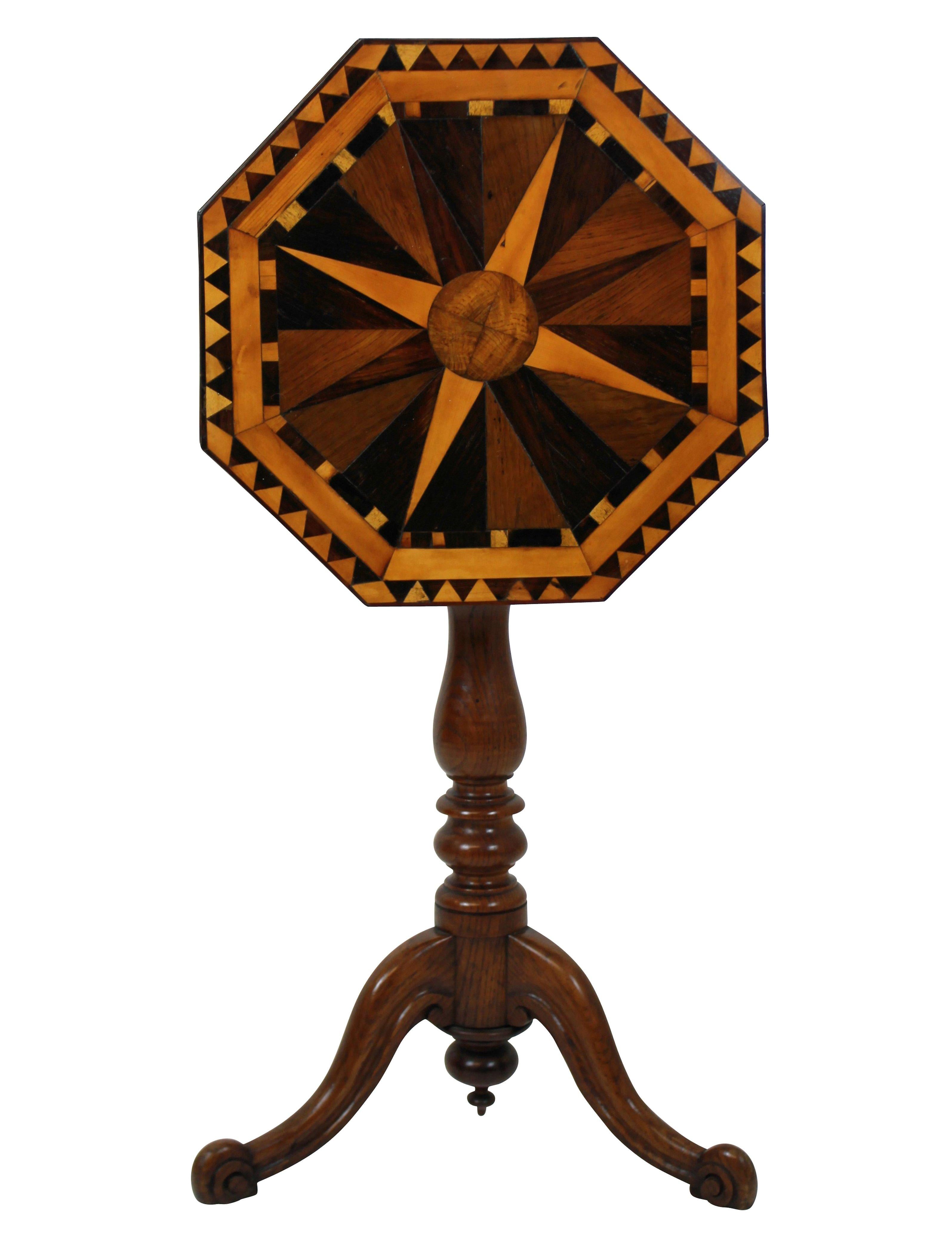 An English pedestal tilt-top table in elm with a fine geometric marquetry top in various English woods depicting a globe and compass. The turned tripod base supporting a tilt-top with scalloped apron with original latch.
  