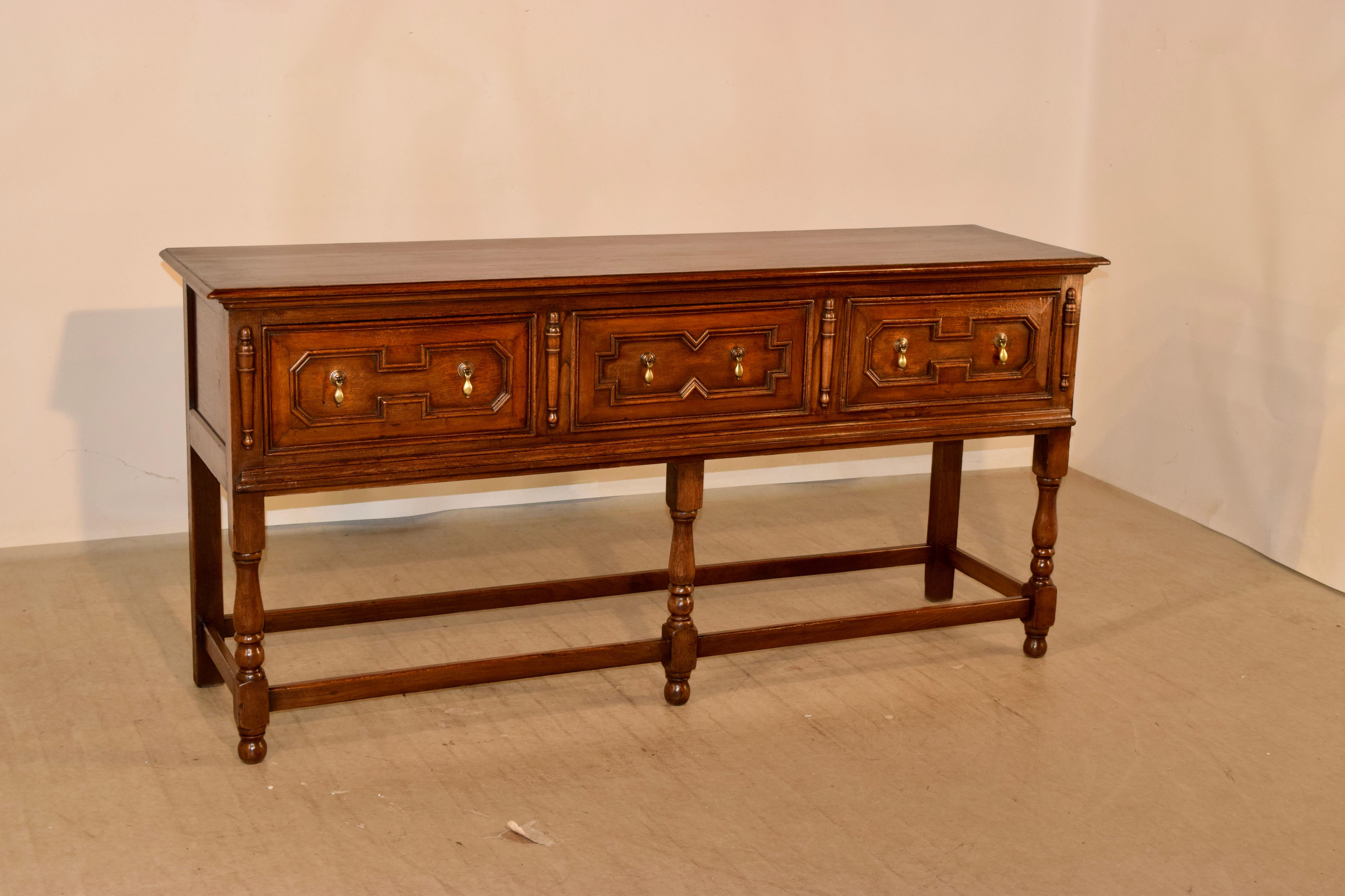 Late 19th century sideboard from England with a beveled edge around the top, following down to paneled sides and two drawers in the front, which have raised geometric panels, and are flanked by applied half turnings. The lower edge of the case is