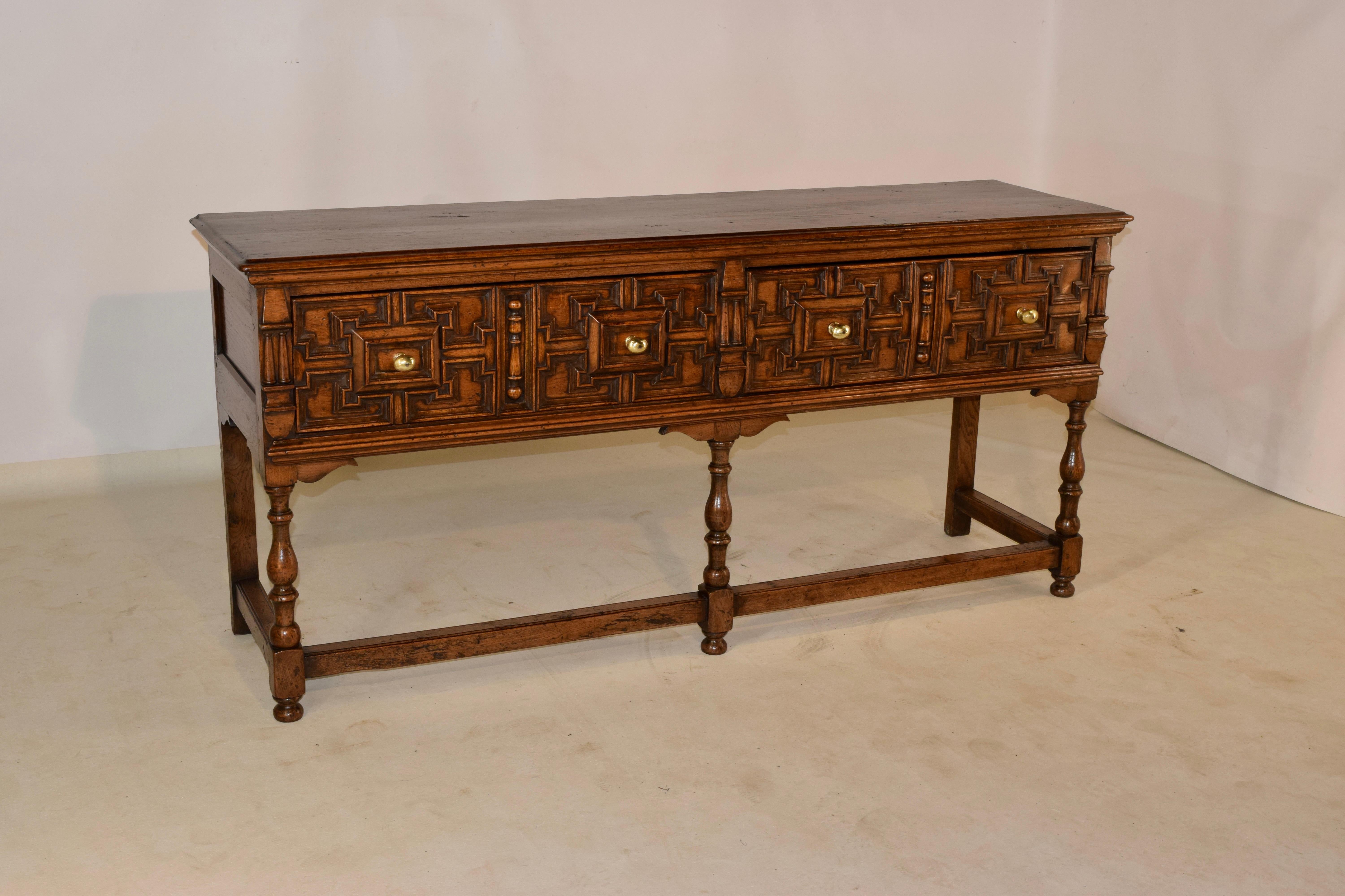 19th century oak sideboard from England with a beveled edge around the top, following down to paneled sides. There are two drawers, both with raised geometric panels and flanked by decorative applied moldings. The piece is supported on simple legs