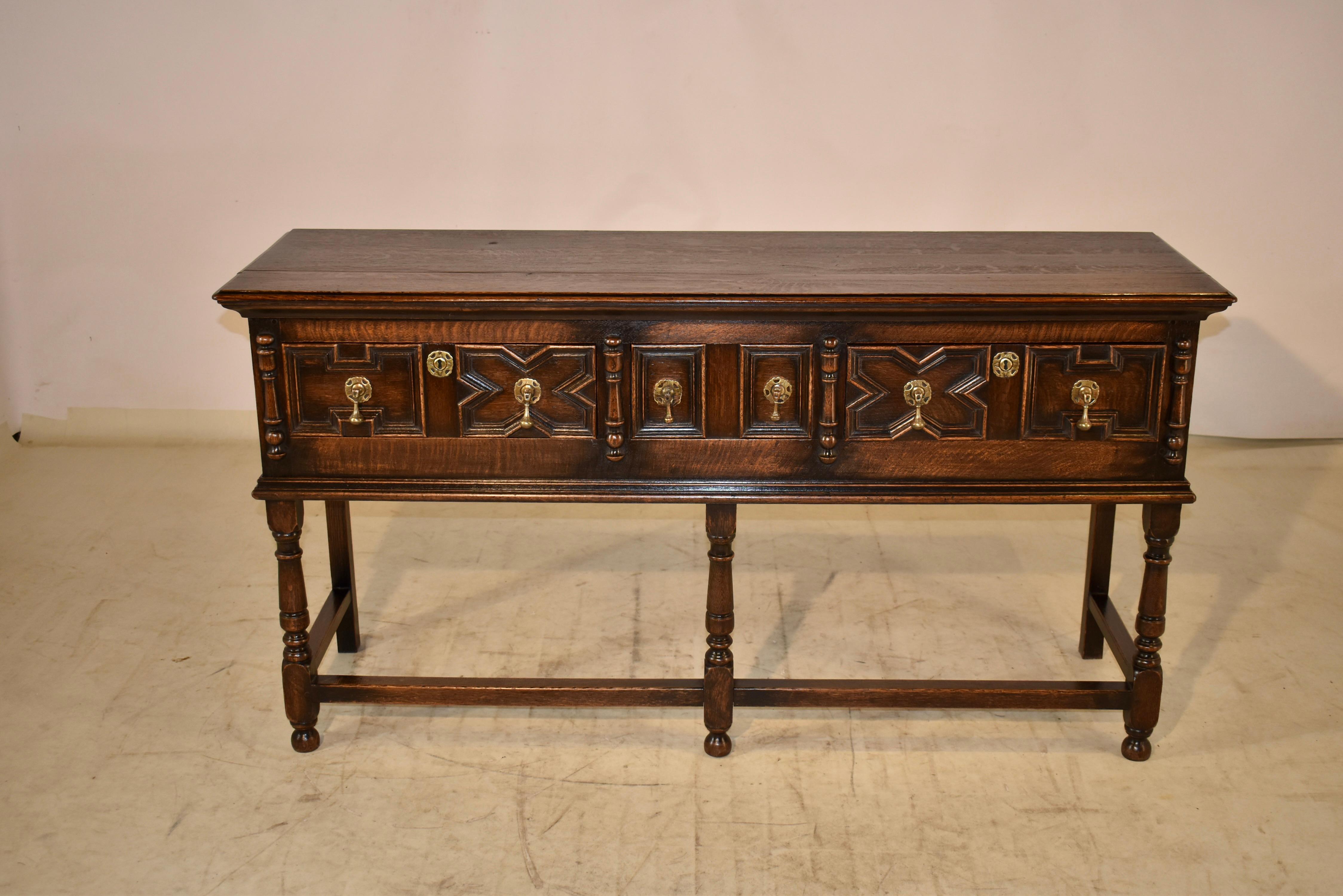 19th century Oak sideboard from England. The top has lovely graining and is beveled around the edge. They follows down to paneled sides and three drawers in the front. The drawer fronts have wonderful geometric paneled designs and lovely hand cast
