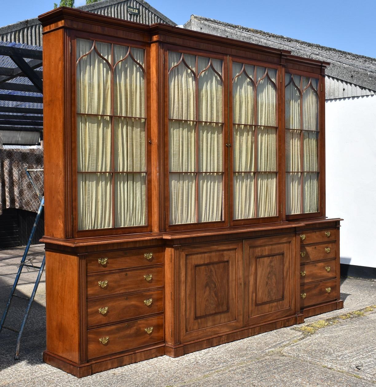 For sale is an impressive George III mahogany breakfront bookcase, attributed to Gillows, with a molded cornice over four large glazed doors, with arched astragals and fabric linings within. Each door is flanked by fluted columns above the base,