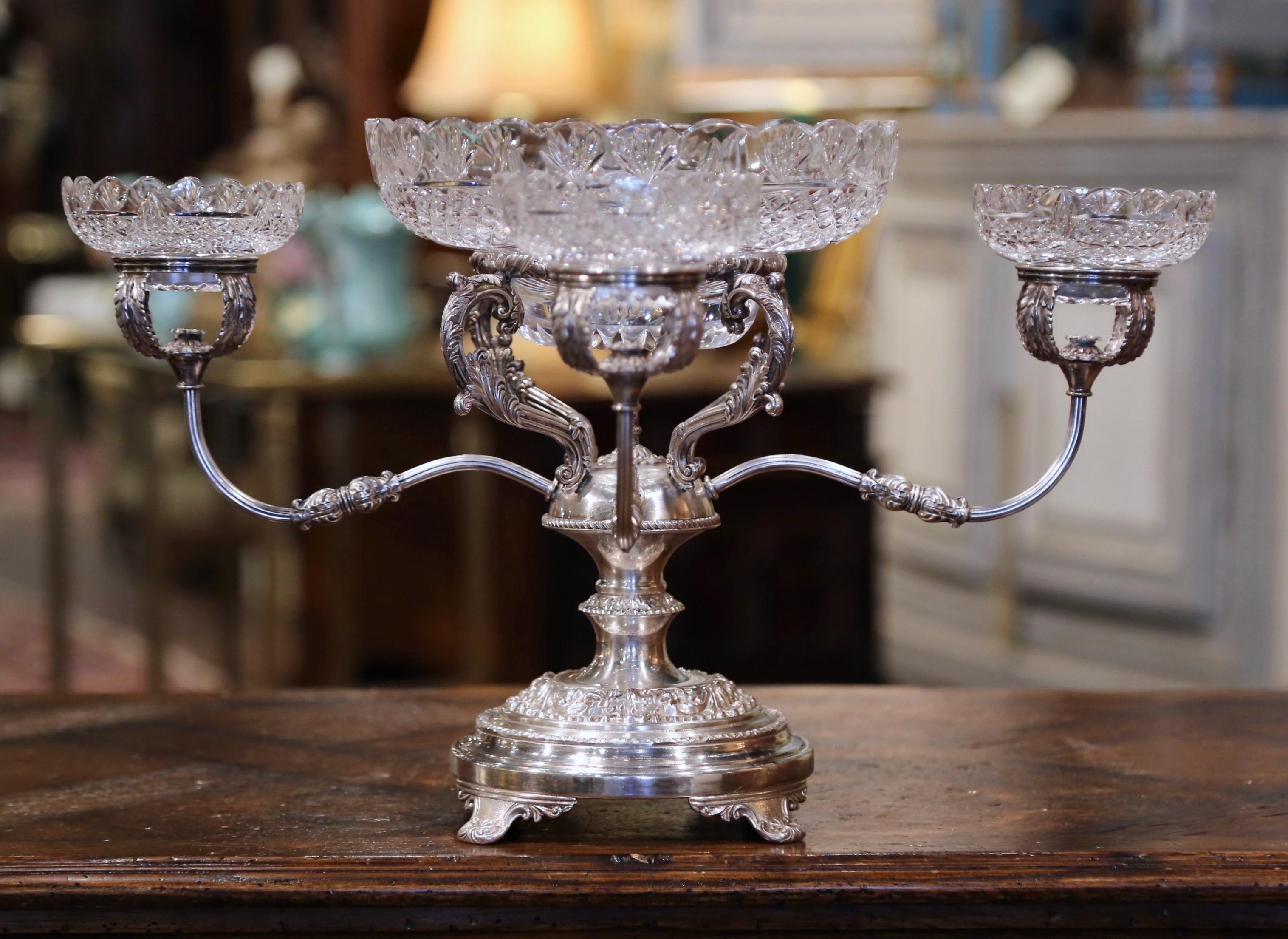 This elegant five-bowl antique epergne was created in England, circa 1890. Made of copper with silver plated, the centerpiece stands on four scrolled feet decorated with shell motifs over a round base embellished with repousse foliage decor. The